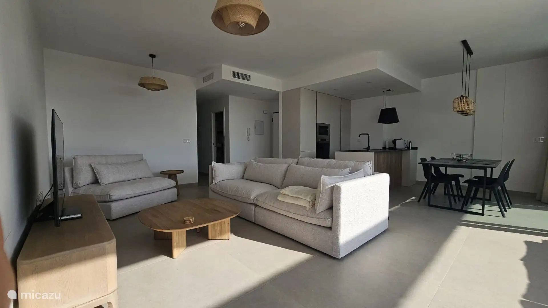 Modernes Wohnzimmer mit offener Küche und bodentiefen Schiebefenstern mit viel Licht