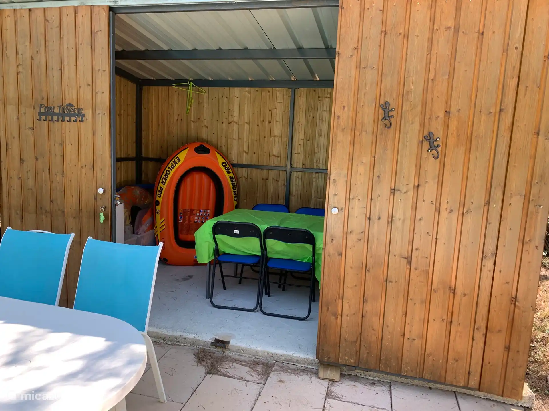 À côté d’un chalet en bois de piscine avec des jouets pour la piscine et aussi une table pour 4