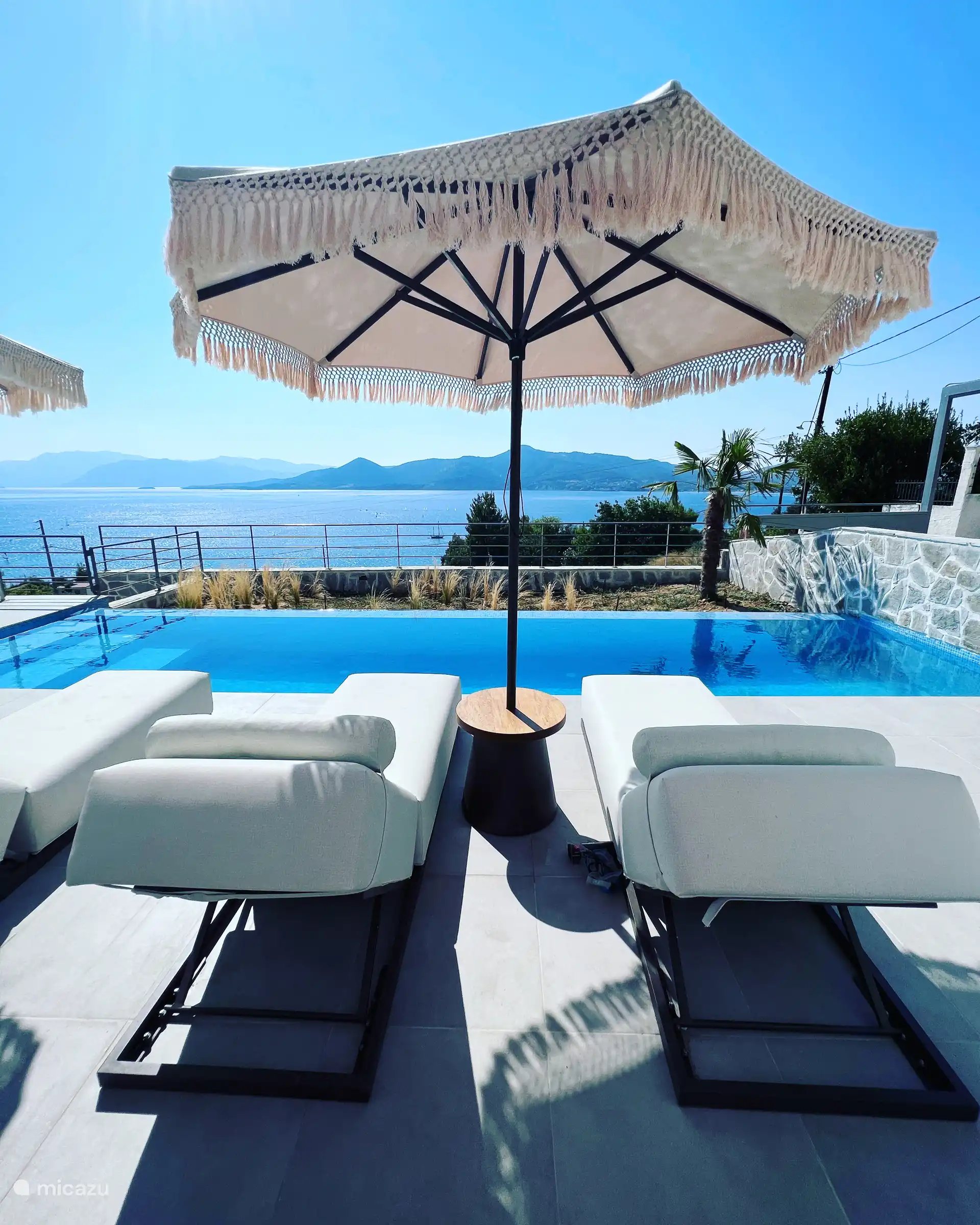 Blick auf das Ionische Meer und die Insel Lefkada von den bequemen Sonnenlounges mit viel Schatten, falls wünschend