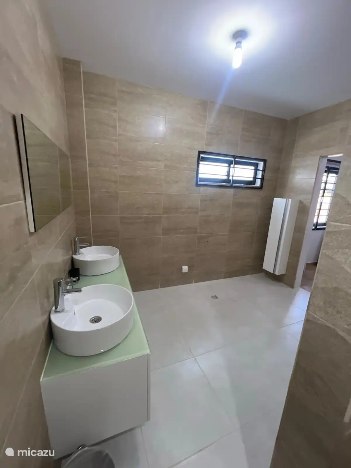 Badkamer en-suite wastafelgedeelte met dubbele wasmeubels en een extra stijlvolle badkamermeubel met legplanken