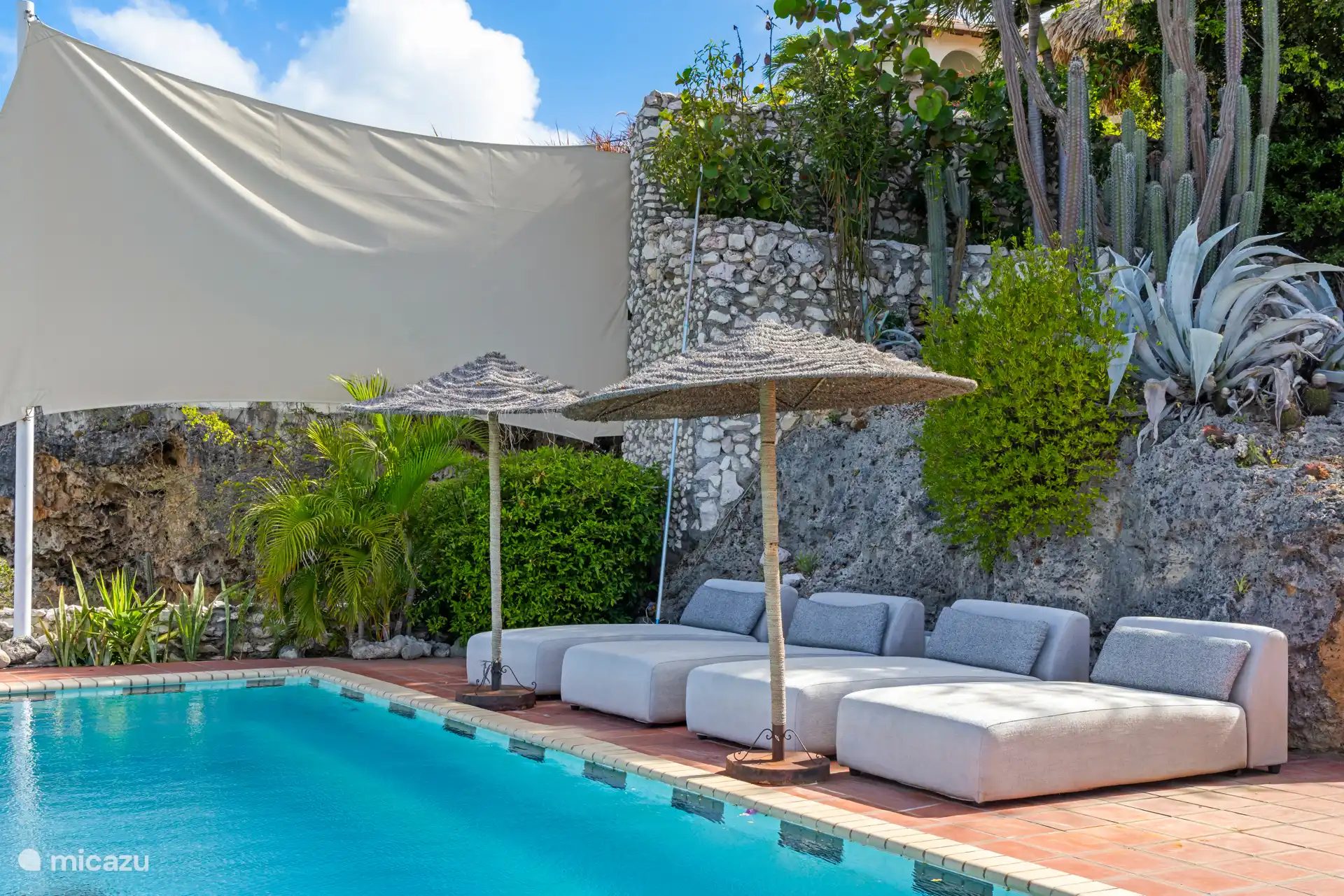 Luxe ligbedden onder een parasol.