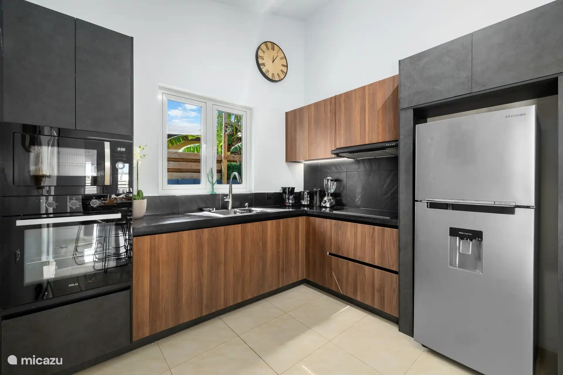 Im Inneren genießen Sie eine zeitgenössische Küche mit satten Holztönen, matten Oberflächen und eleganten schwarzen Arbeitsplatten.