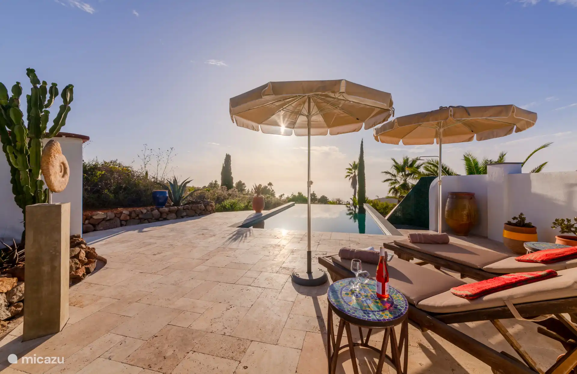 Von deiner Terrasse mit bequemen Sonnenliege und Gartenmöbeln aus hast du einen fantastischen Blick aufs Meer.