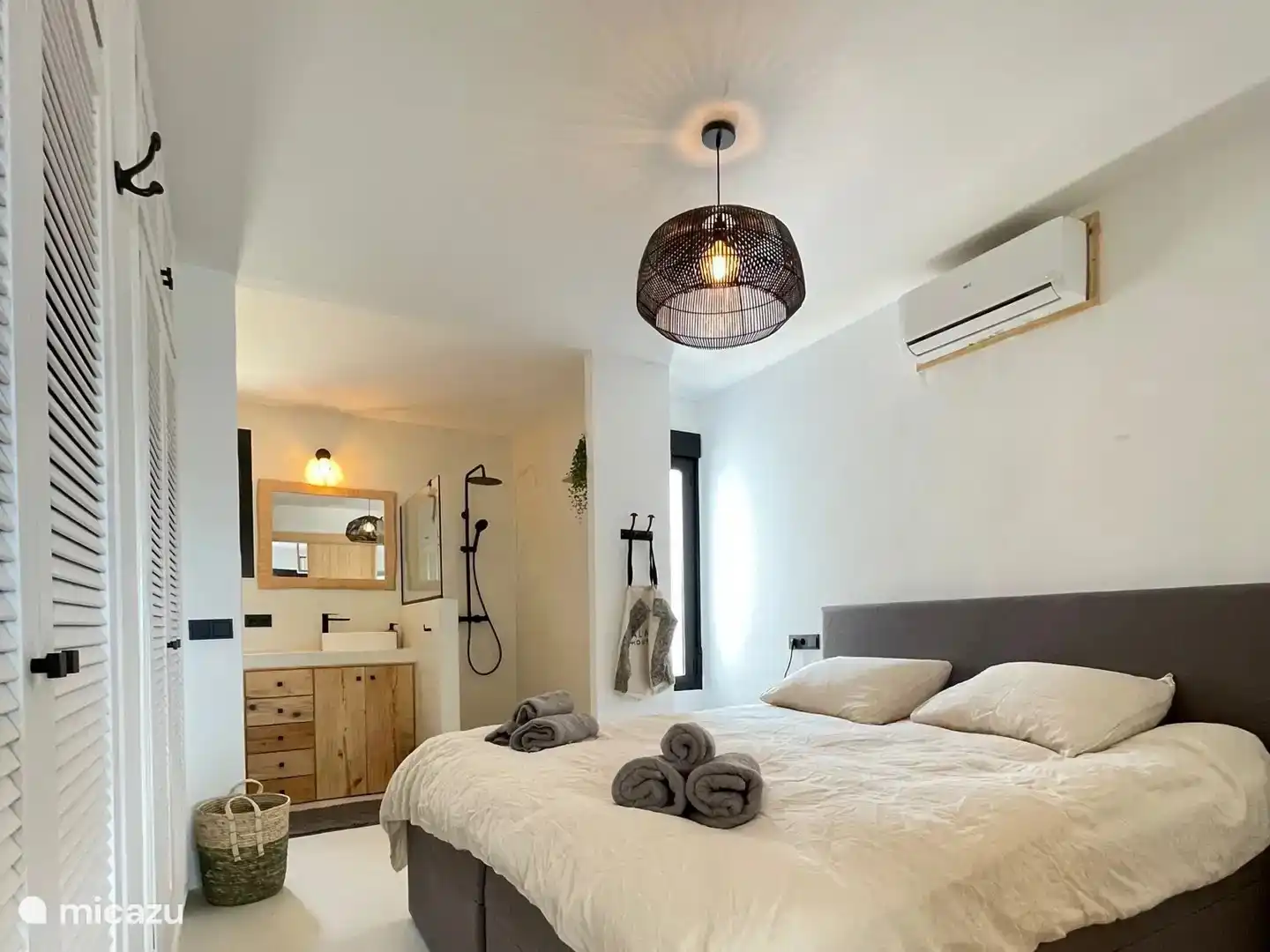 Geräumiges Schlafzimmer mit Klimaanlage, großem Doppelbett (180x210), viel Platz im Kleiderschrank und integriertem Bad mit begehbarer Dusche, Waschbecken und Toilette.