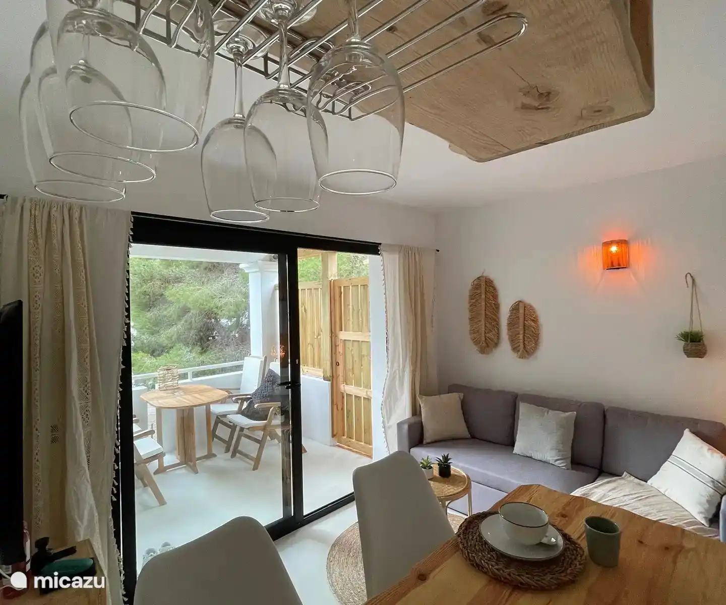 Gemütliches Wohnzimmer im Ibiza-Stil mit integrierter Küche. Vom Wohnzimmer aus hat man einen Blick aufs Meer.