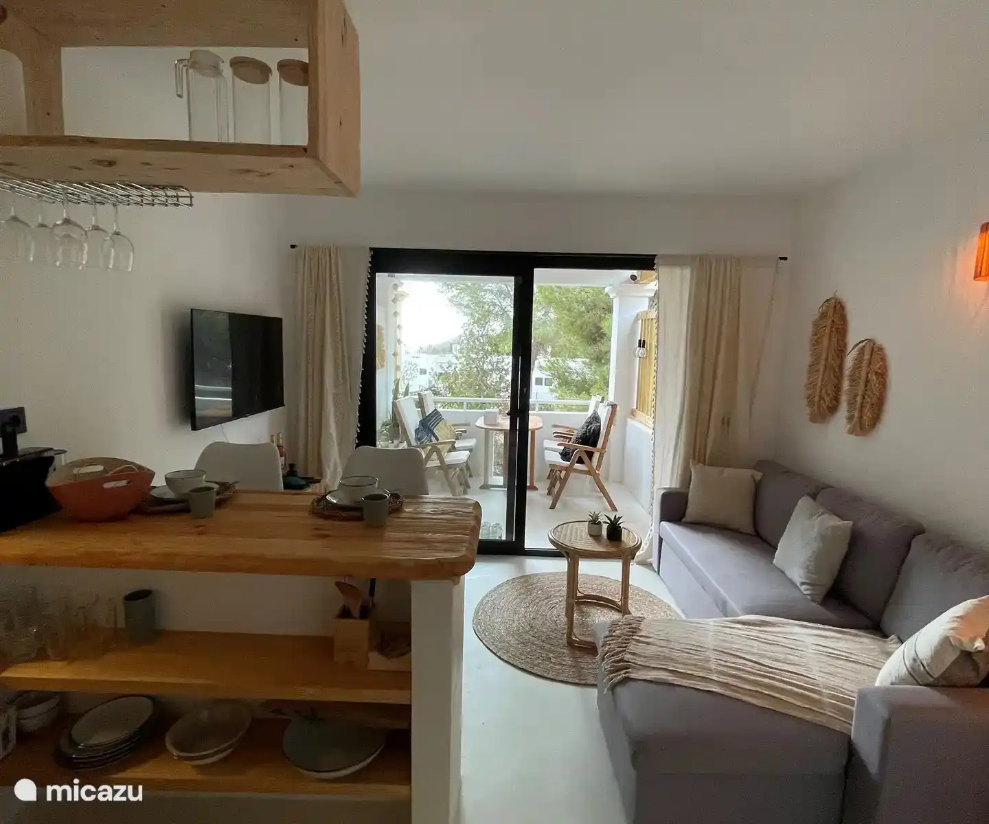 Gemütliches Wohnzimmer im Ibiza-Stil mit integrierter Küche. Vom Wohnzimmer aus hat man einen Blick aufs Meer.