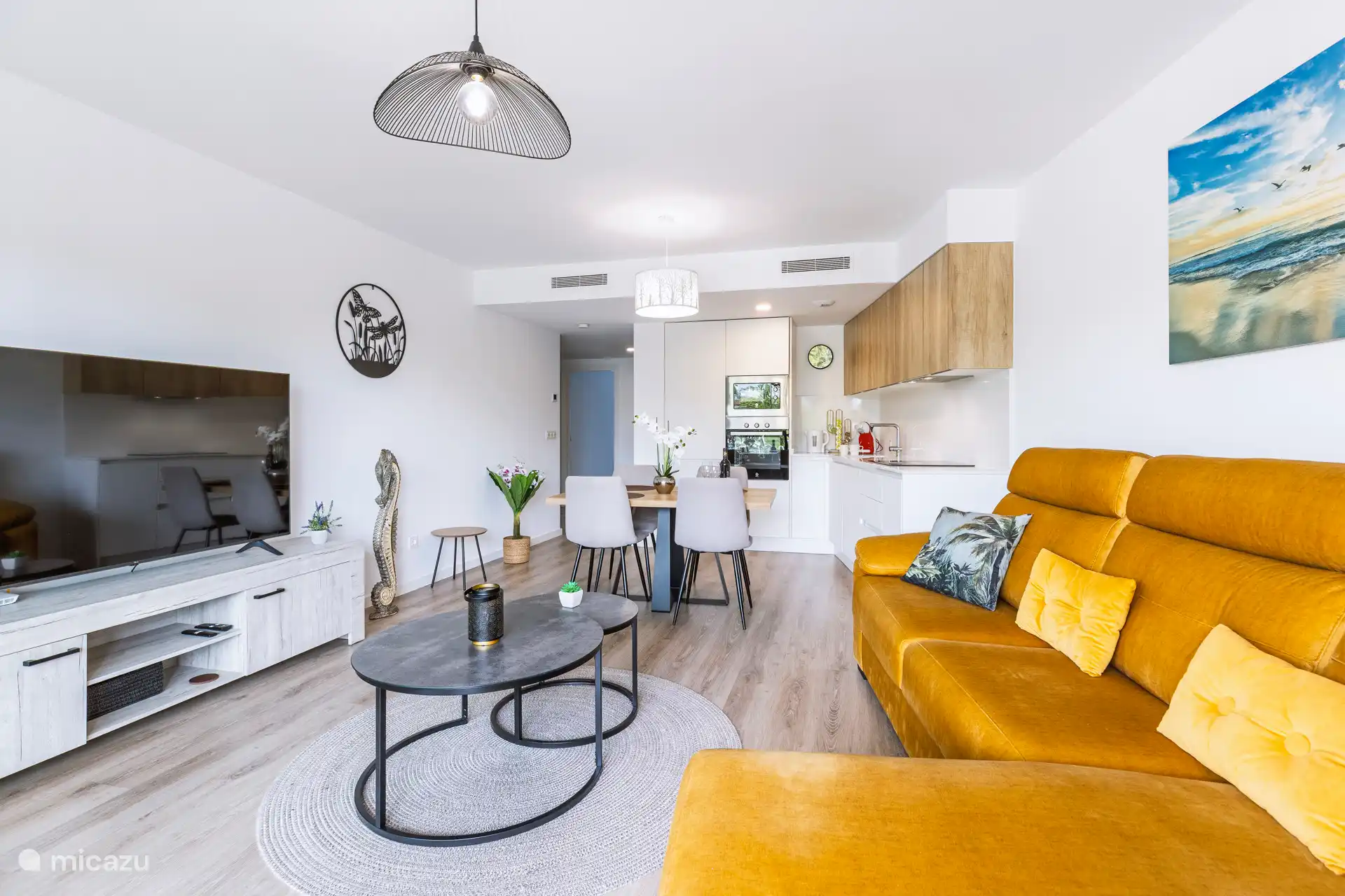 Sitzbereich mit Fernseher und offene Küche mit Esstisch.