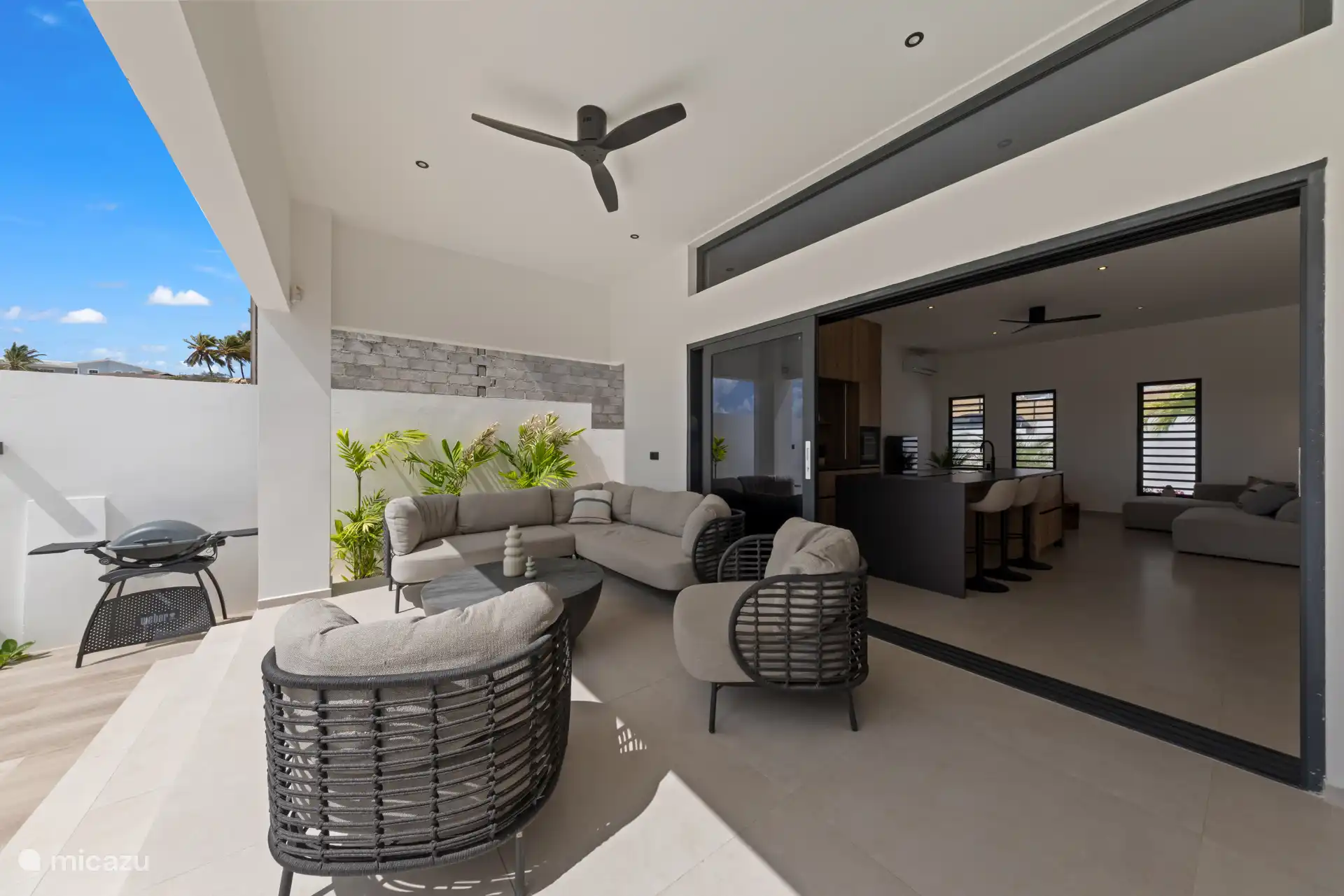 Royale buitenliving met lounge, plafondventilator en directe verbinding met binnen.