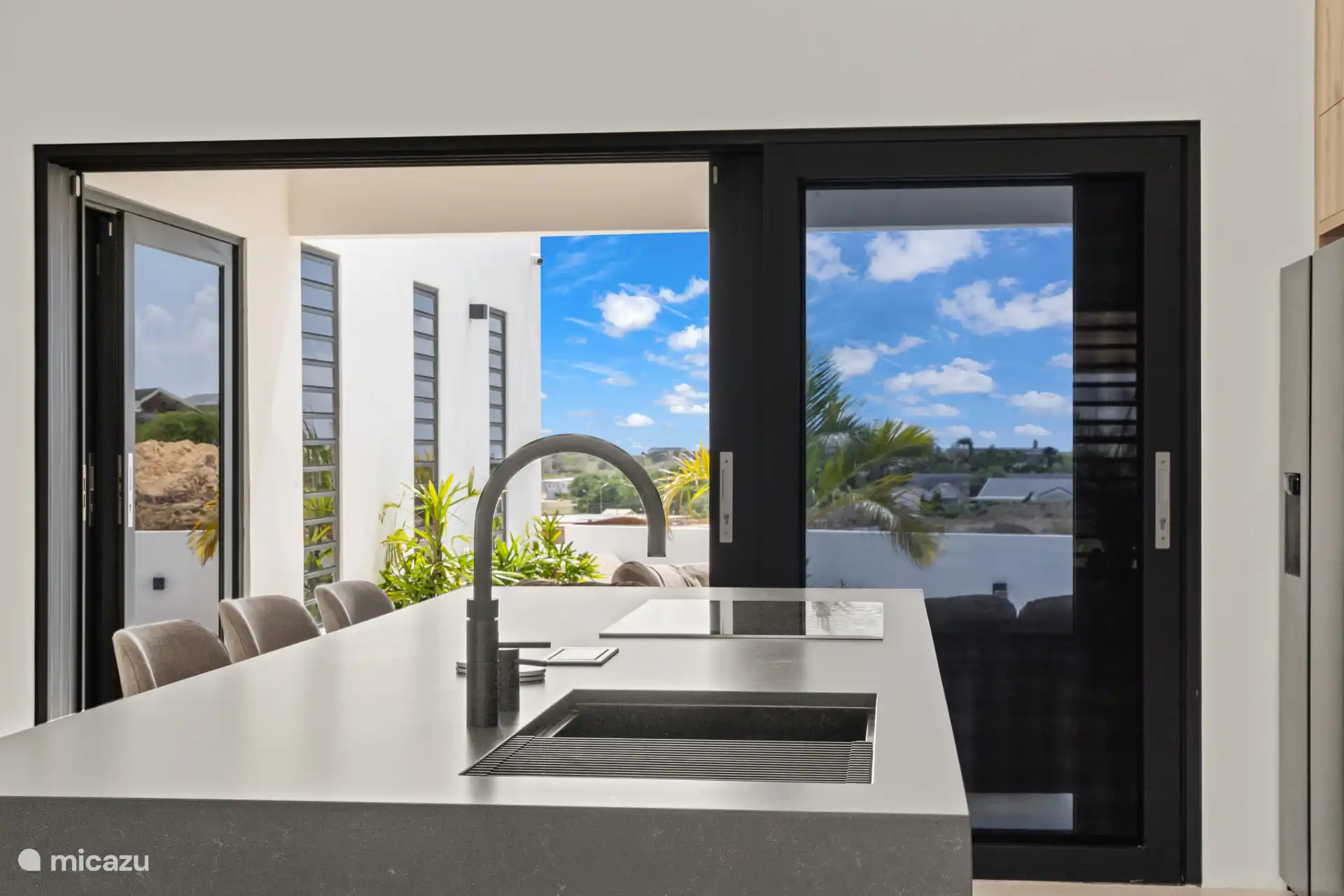 Uitzicht vanuit de keuken richting het terras, met grote schuifdeuren en veel licht.