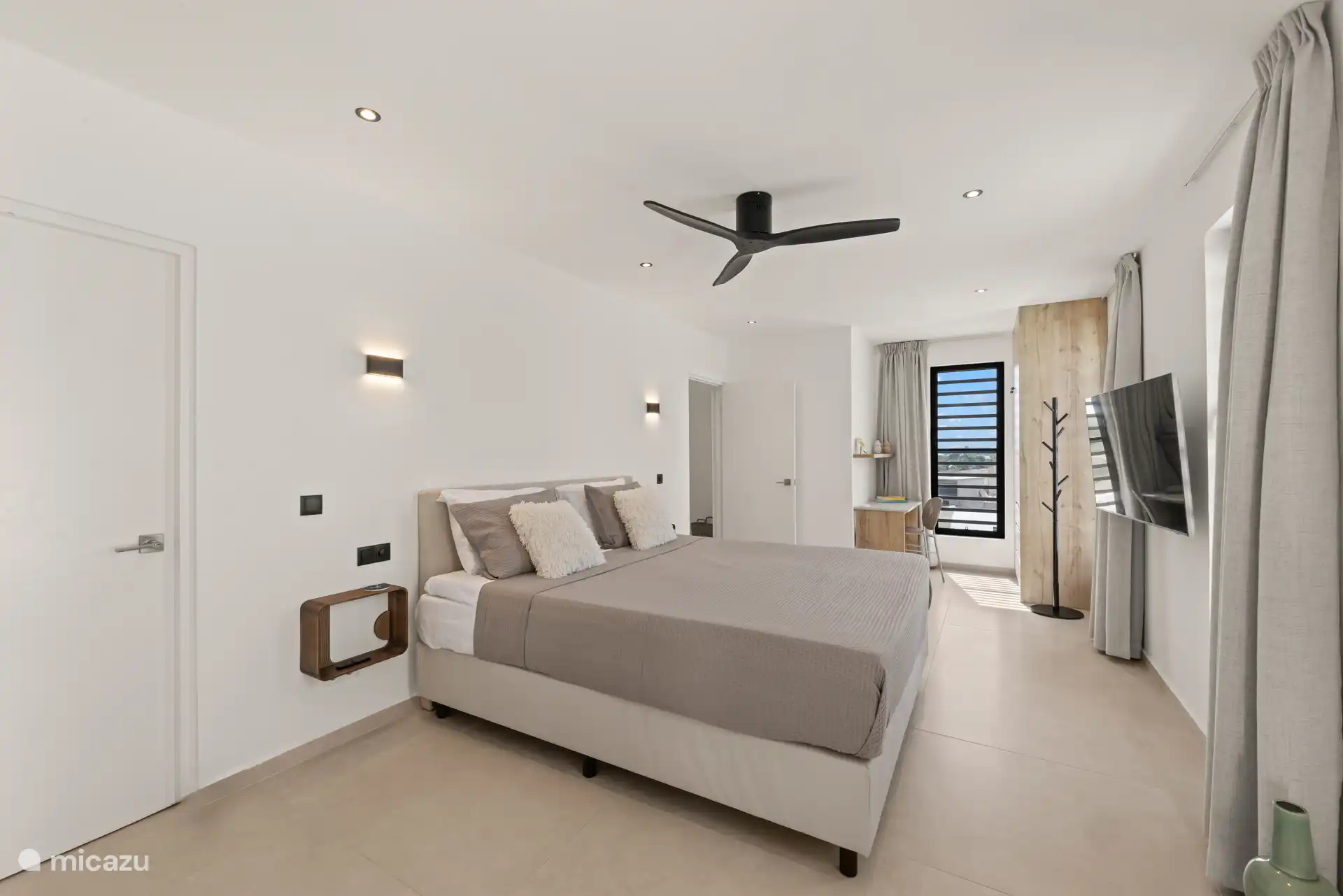 Comfortabele slaapkamer met tv, airconditioning en een rustige, lichte sfeer.