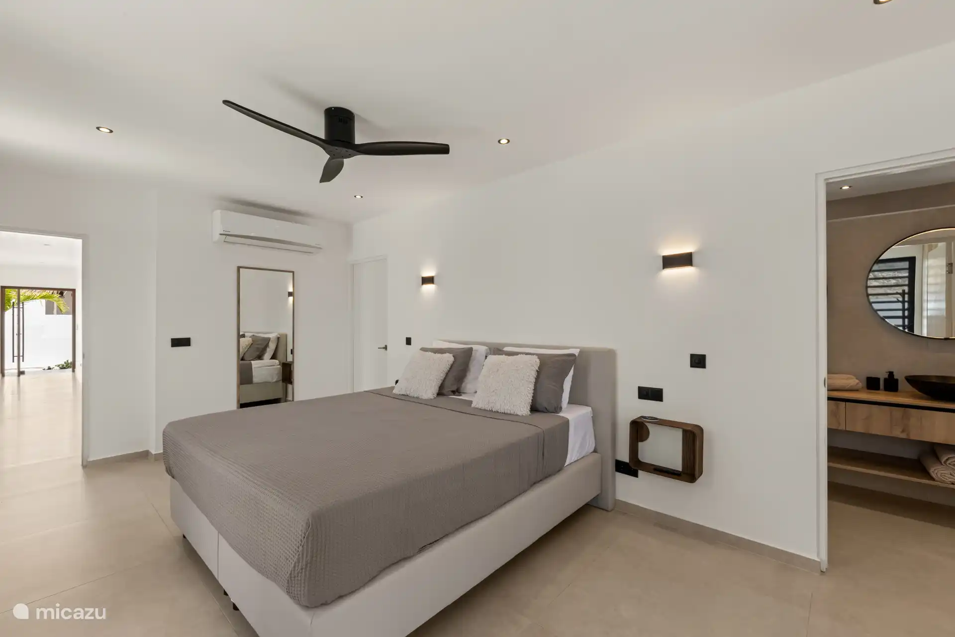 Slaapkamer met comfortabel bed, plafondventilator en ensuite badkamer.