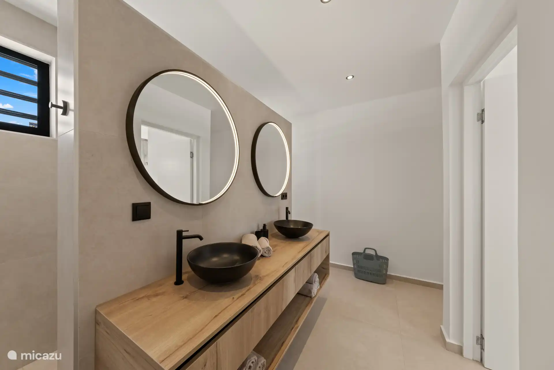 Stijlvolle badkamer met dubbele wastafel, grote spiegels en luxe afwerking.