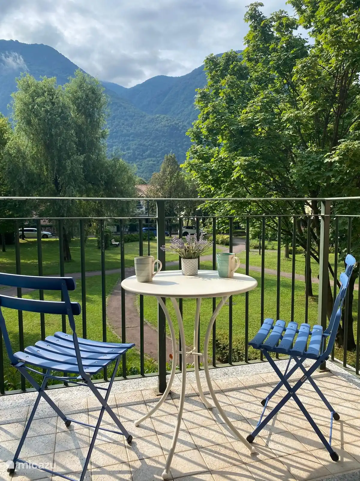 het balkon met tafel en stoeltjes met prachtig uitzicht over de bergen en de binnentuin