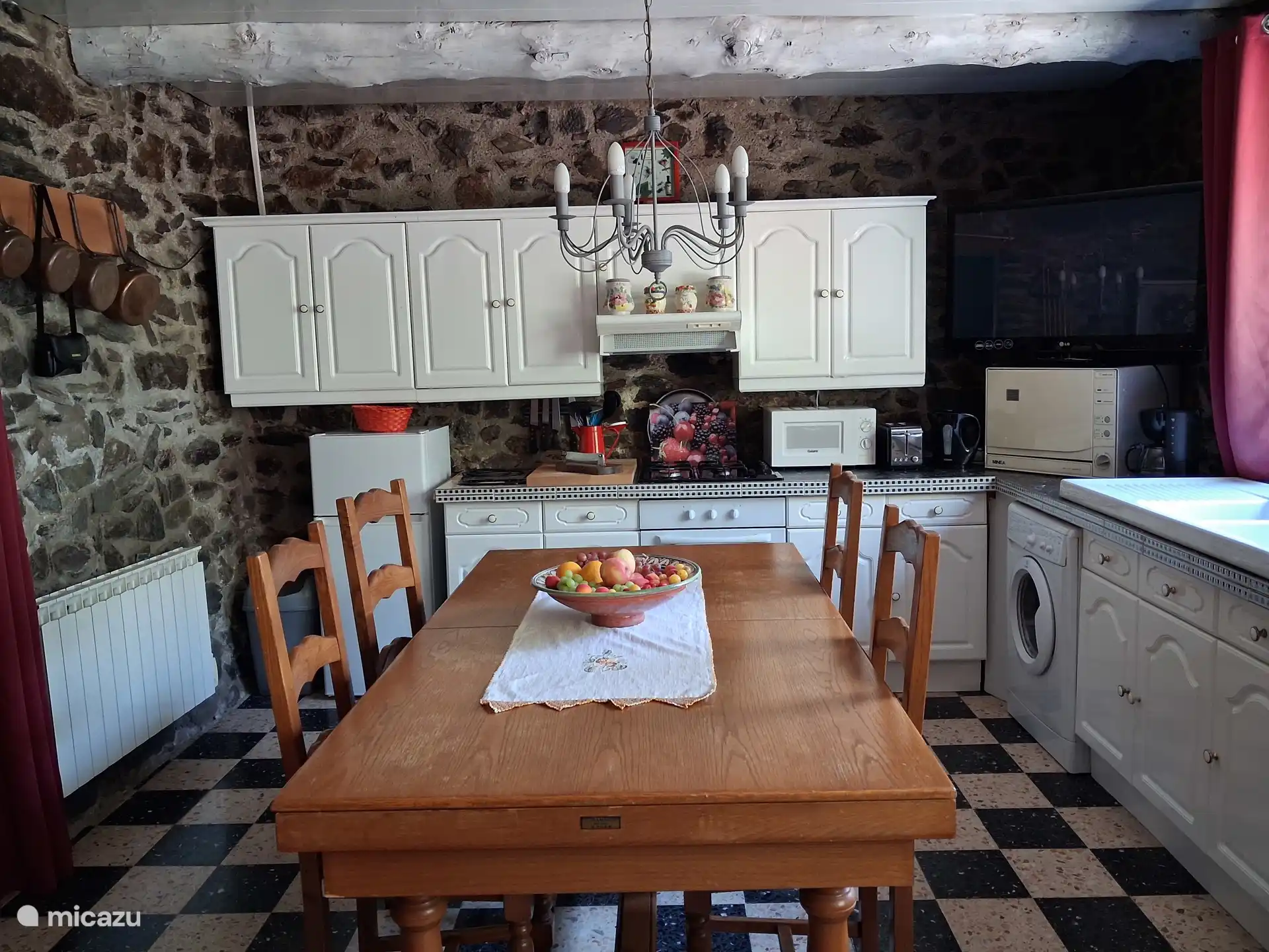 Keuken met gasfornuis en oven, vaatwasser, magnetron, wasmachine, koelkast. 