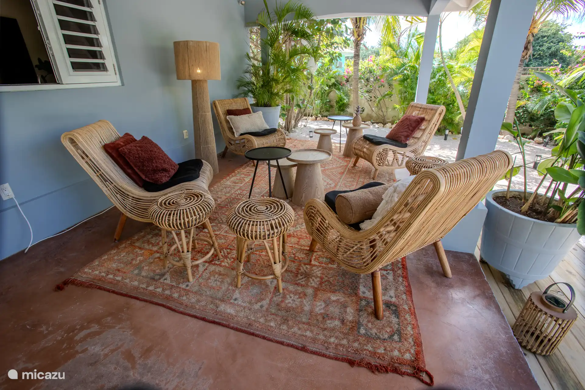 Una zona lounge encantadora con 4 sillones de ratán y mesas agradables