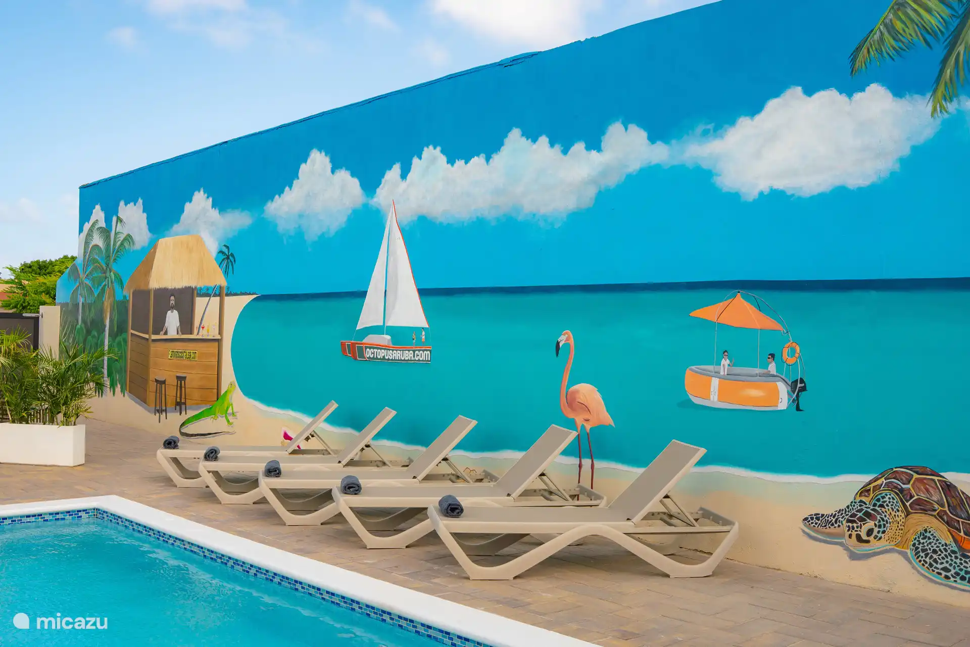 Detalles artísticos junto a la piscina con un mural colorido, que crea un aspecto tropical y atmosférico.