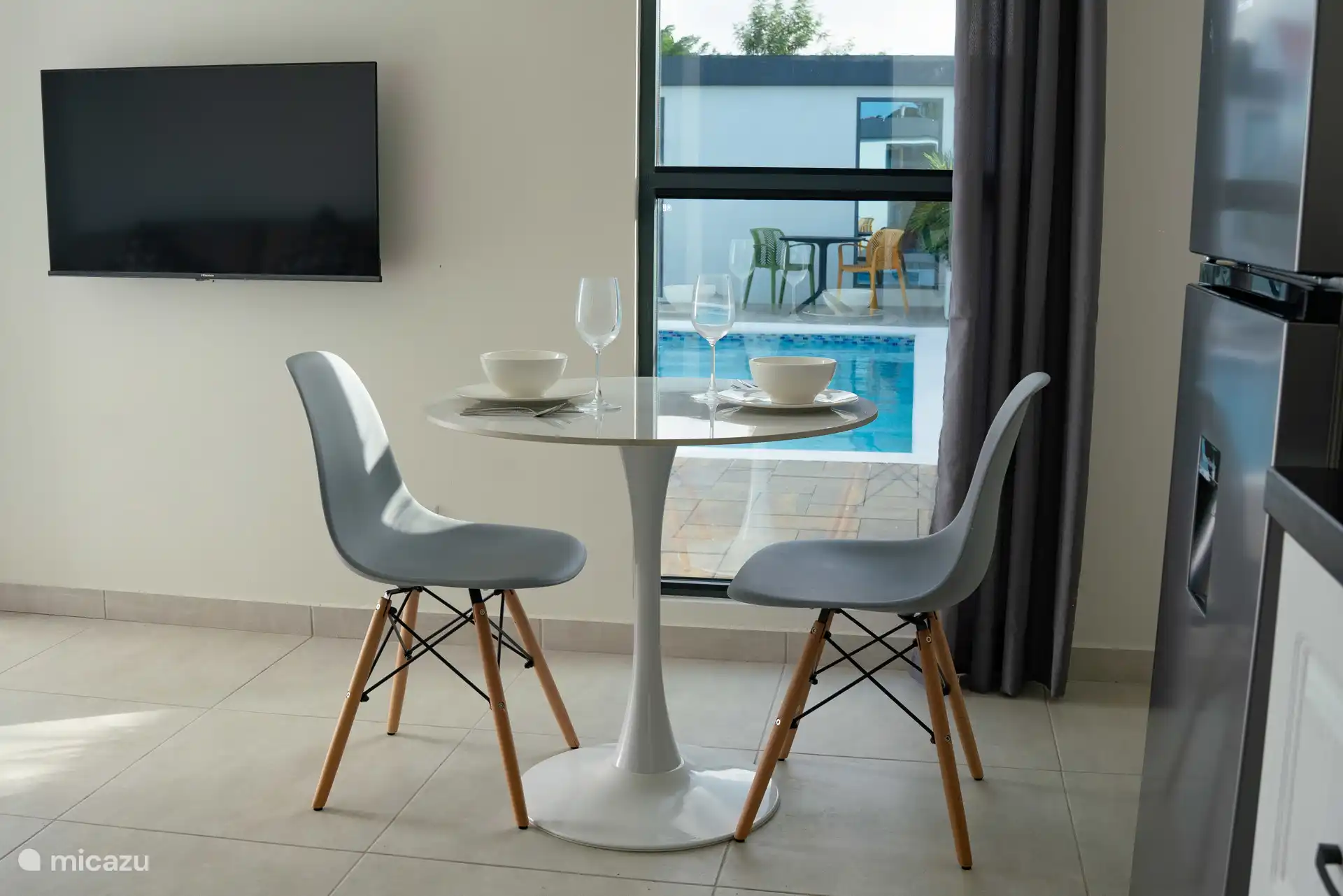 Comedor con asientos para dos, situado junto a la ventana con vistas a la piscina.