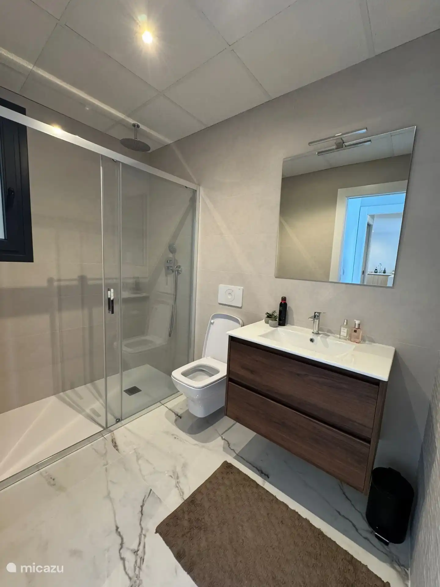 Baño moderno en suite, situado junto al dormitorio principal con un lavabo amplio, ducha de lluvia y inodoro colgante. 