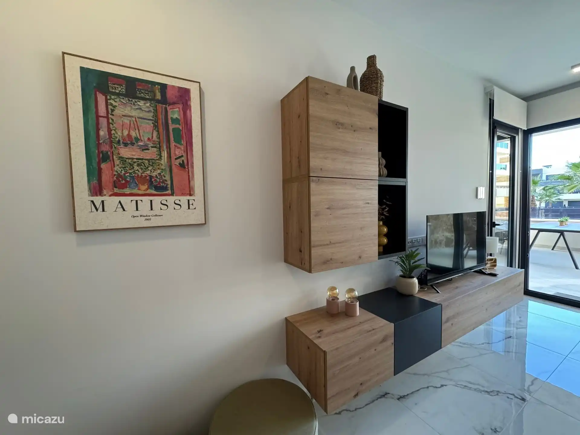 Salón con gran televisor inteligente, terraza con vistas, palmerto y piscina.