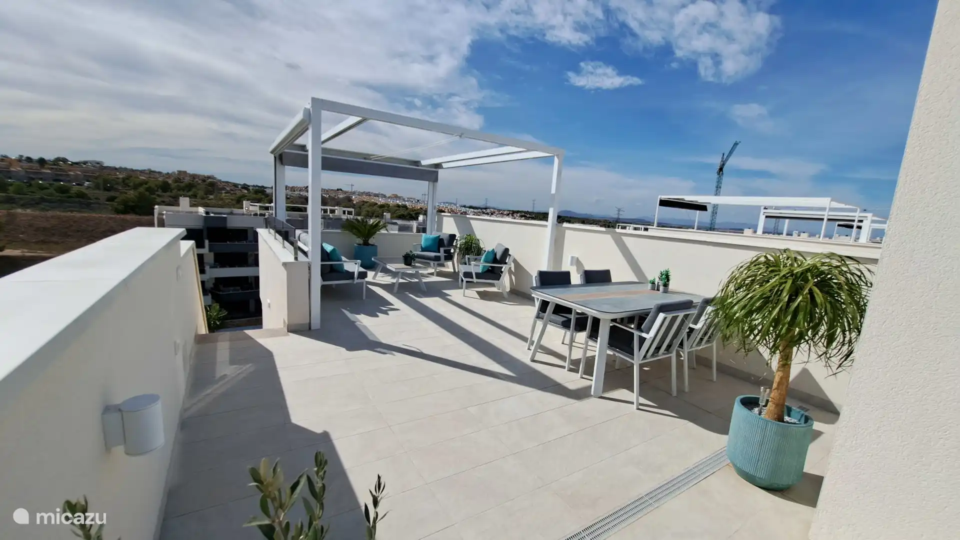 the spacious roof terrace with a pergola, a dining table, lounge set