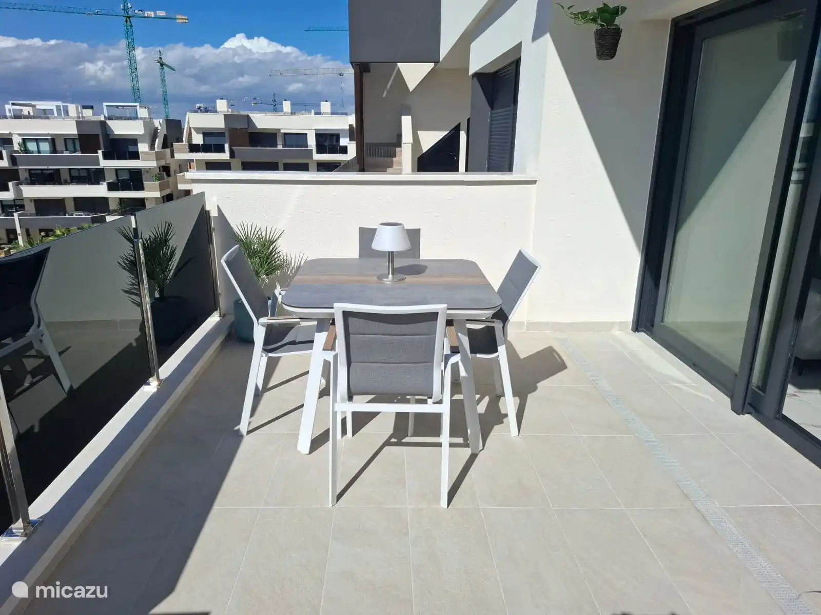 spacious balcony with an electric awning with a view of the apartment complex and a view of the communal swimming pool and garden 