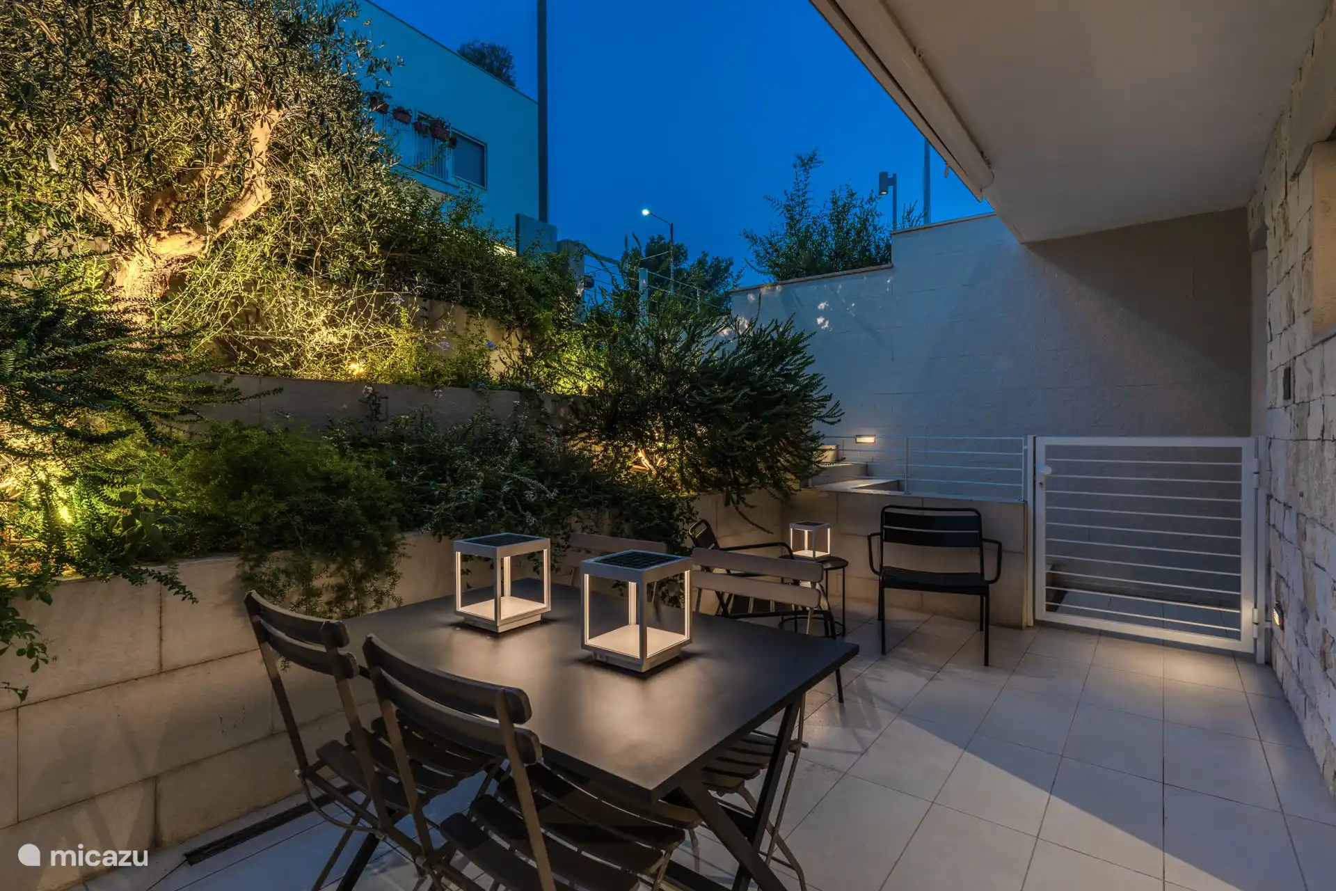 Terras met tuin. Tafel voor 4 personen en 2 ligstoelen met een klein tafeltje in het midden.
Zonne-tuinverlichting.