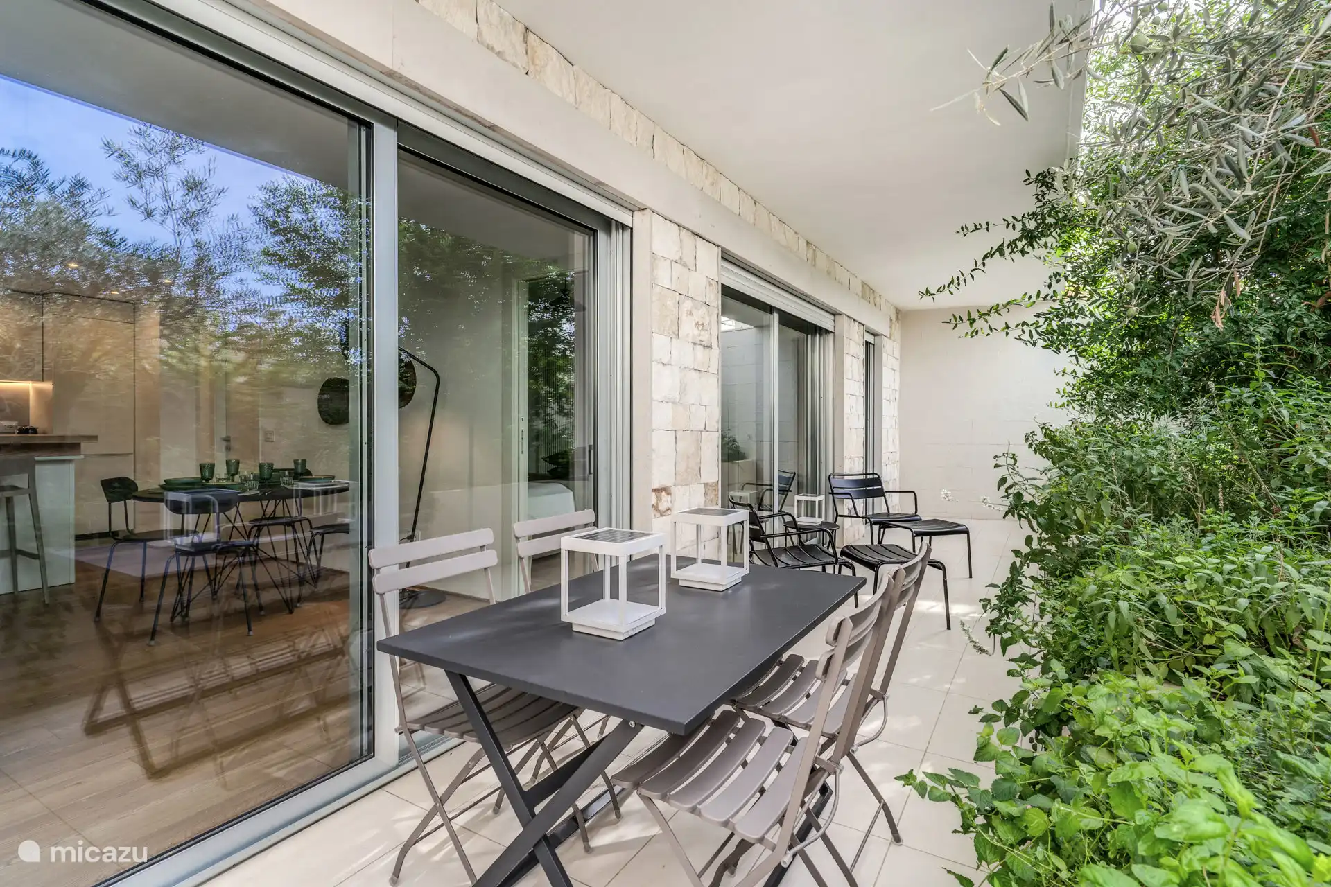 Terras met tuin. Tafel voor 4 personen en 2 ligstoelen met voetensteun en een kleine tafel in het midden.
Zonne-tuinverlichting.