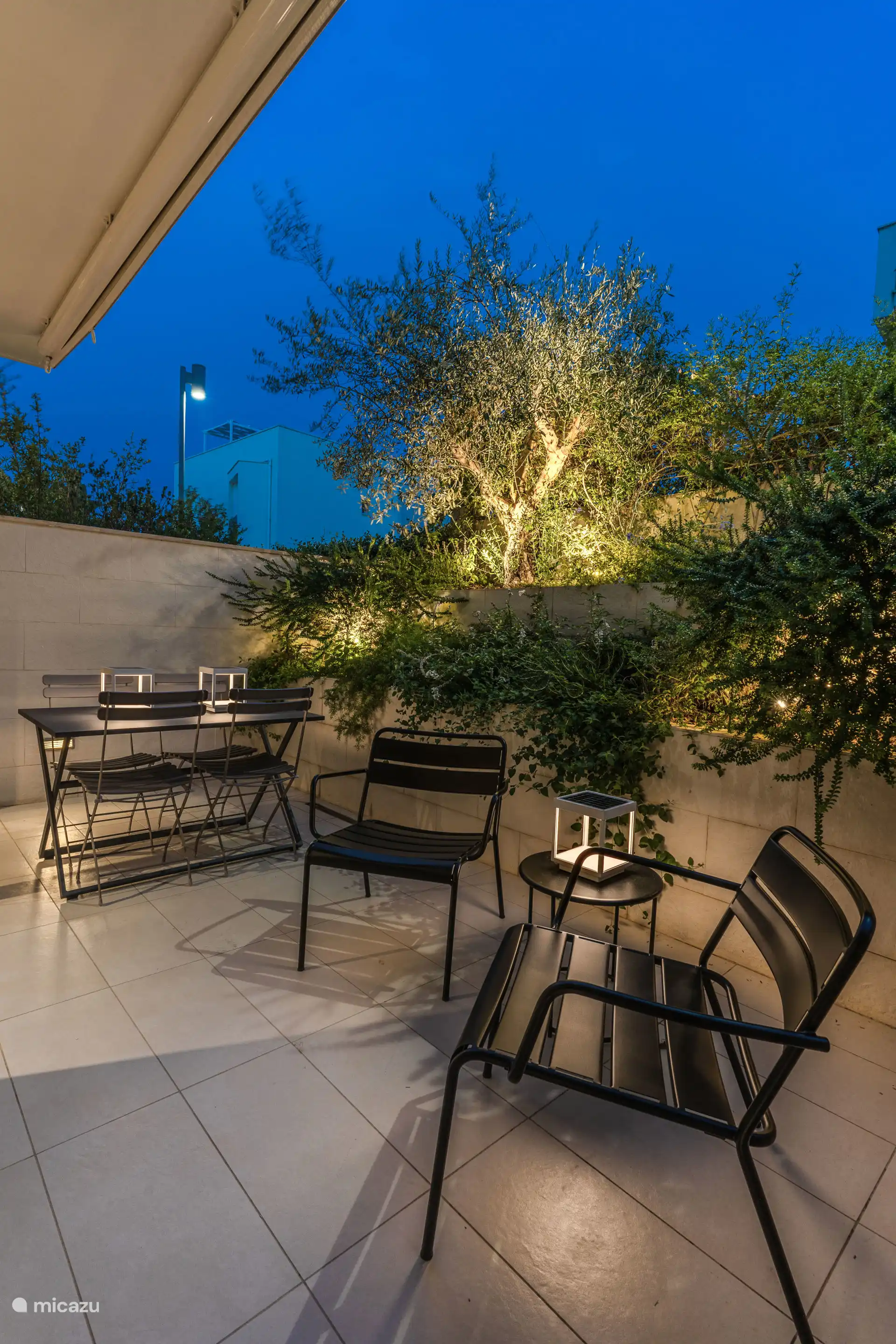 Terras met tuin. Tafel voor 4 personen en 2 ligstoelen met een klein tafeltje in het midden.
Zonne-tuinverlichting.