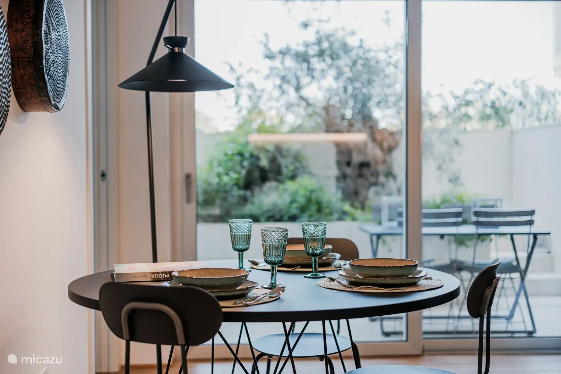 Eettafel met uitzicht op de tuin en een groot raam met een hanglamp boven de tafel om een ontspannen sfeer te creëren.