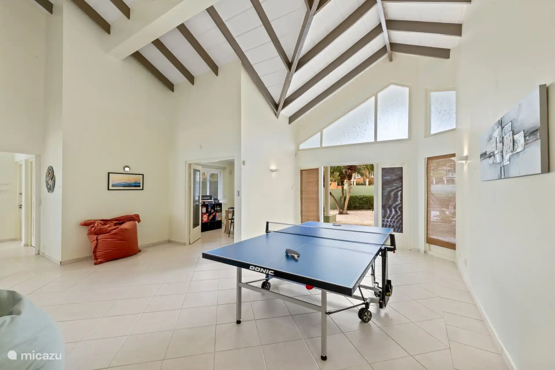 Speelruimte met een full-size pingpongtafel en een aparte bureauhoek, allemaal onder hoge gewelfde plafonds.