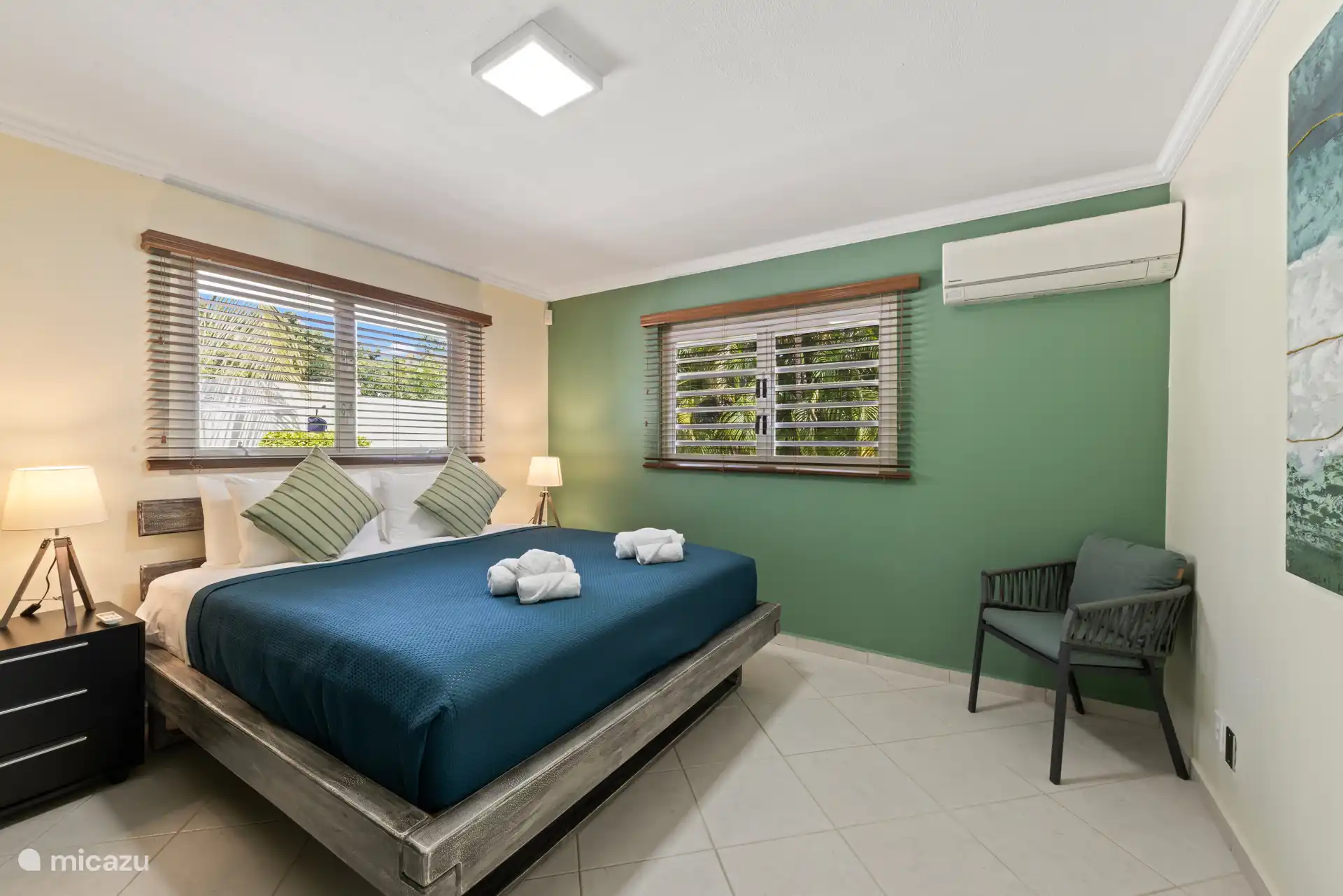 Tweede slaapkamer met een kingsize bed, airconditioning, uitzicht op de tuin en zacht licht voor een rustige, rustige nachtrust.