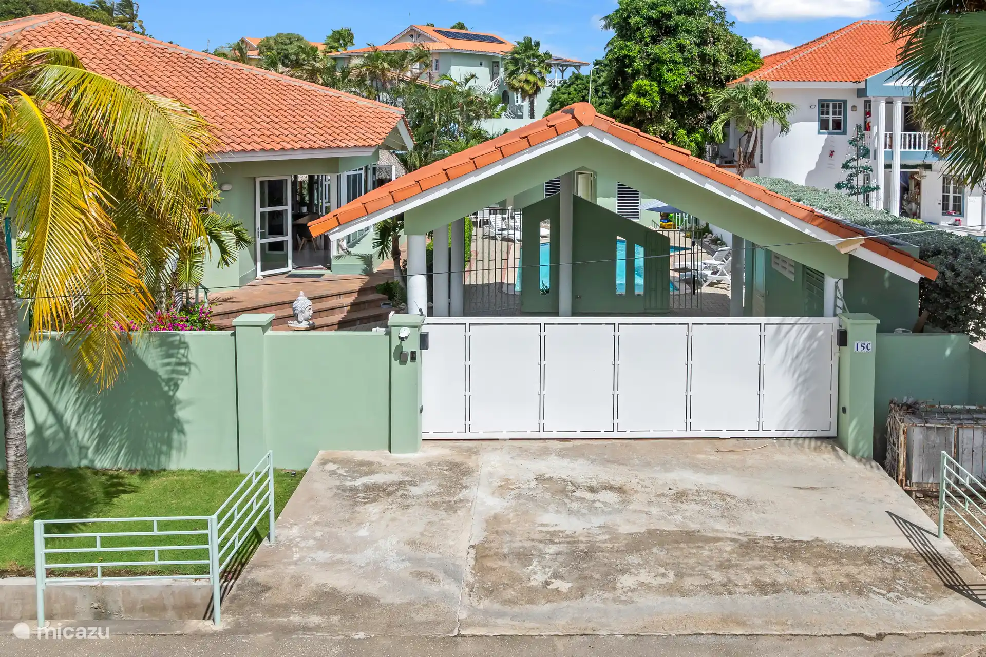 Beveilig een afgesloten ingang met overdekte carport en directe toegang tot de villa en het zwembadterras achter de muren.