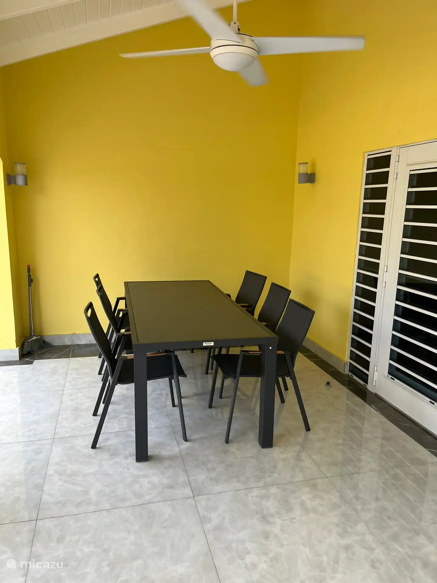 Porche couvert avec une grande table et 6 chaises