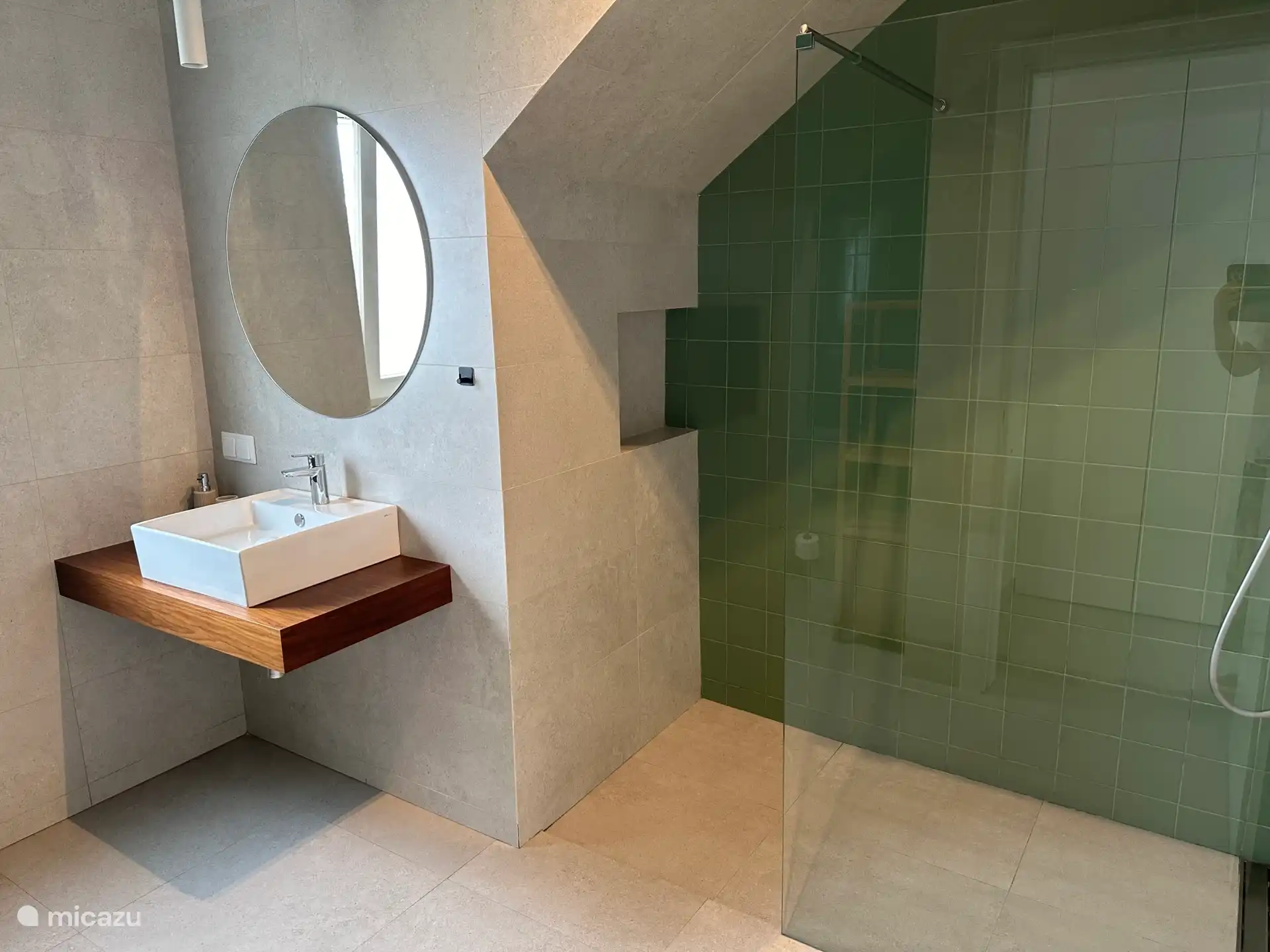 De badkamer op de begane vloer. Voorzien van een grote inloopdouche, een wastafel, bergkasten en een WC.