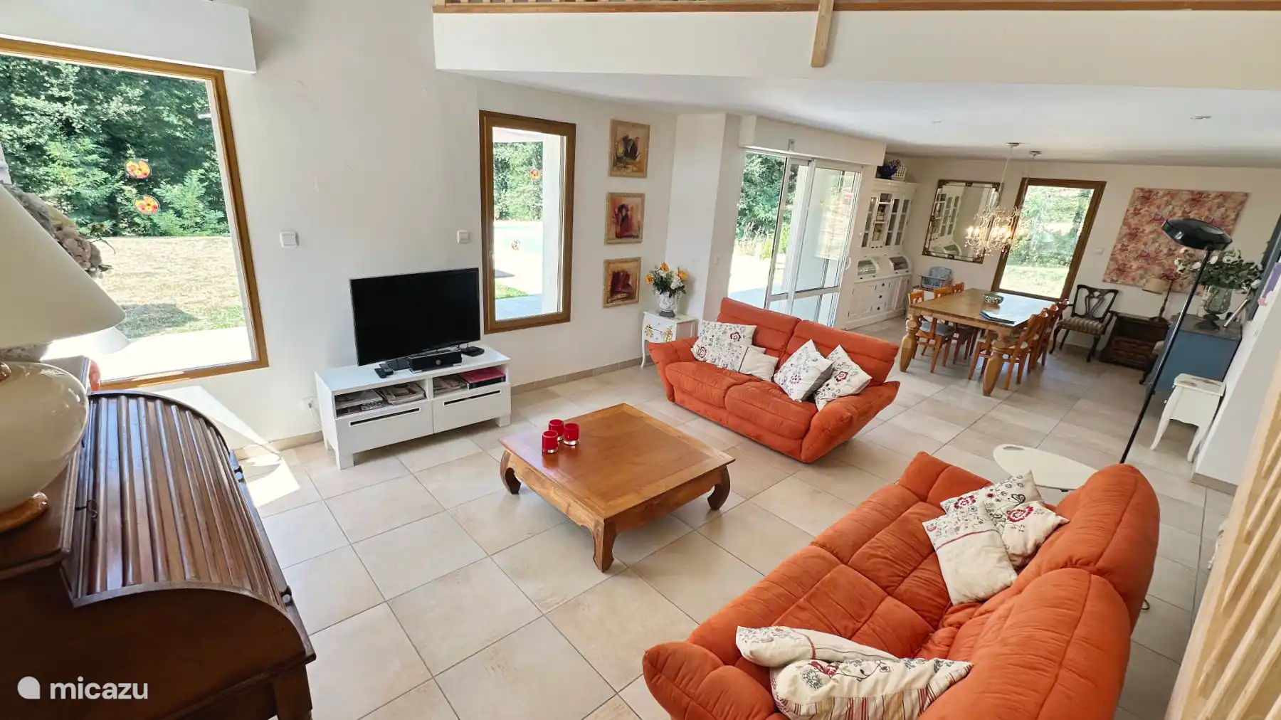 el amplio salón seguido por el comedor. Las puertas correderas dan acceso a la terraza, el jardín y la piscina