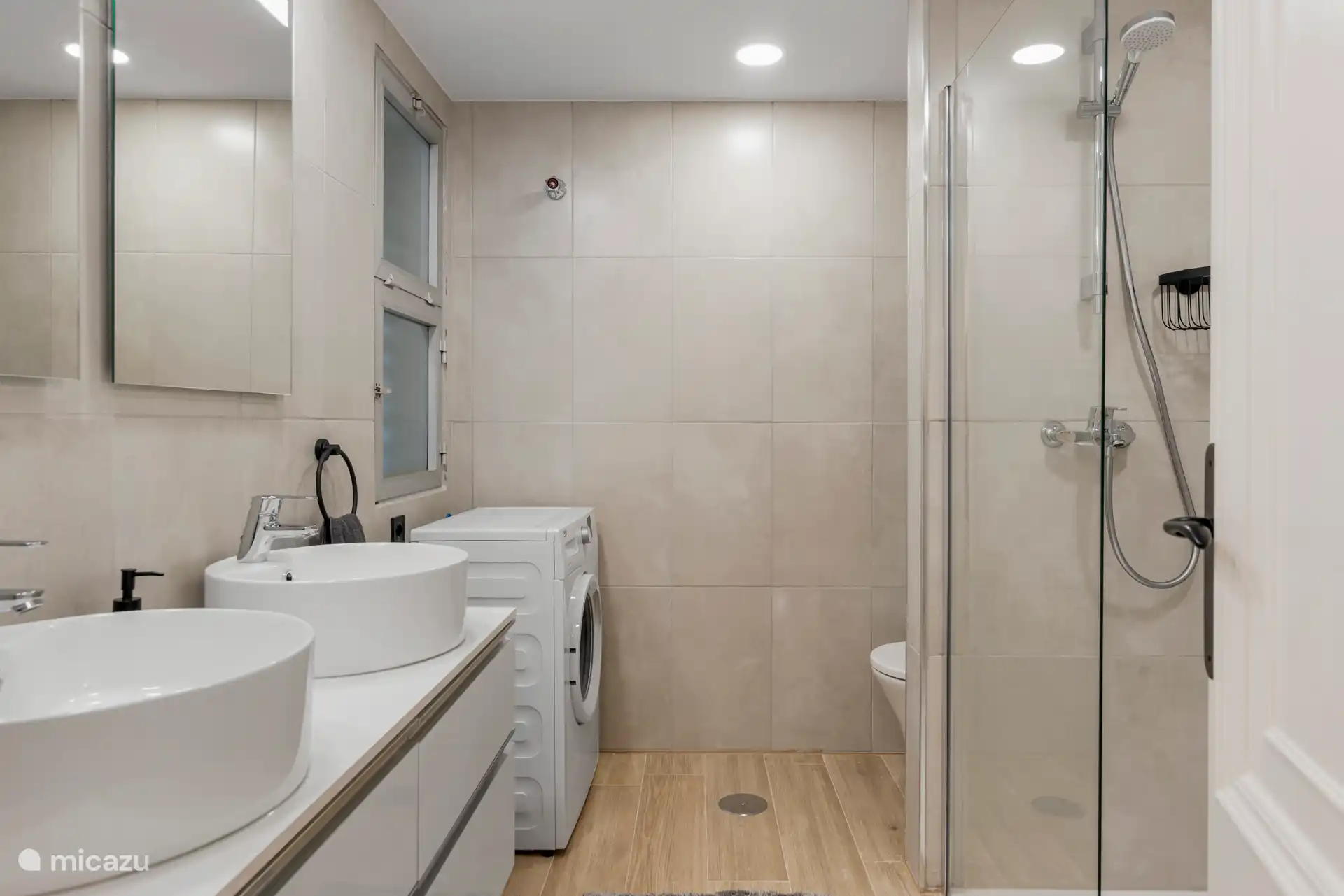 Baño con ducha a nivel de camilla, lavabo doble y lavadora