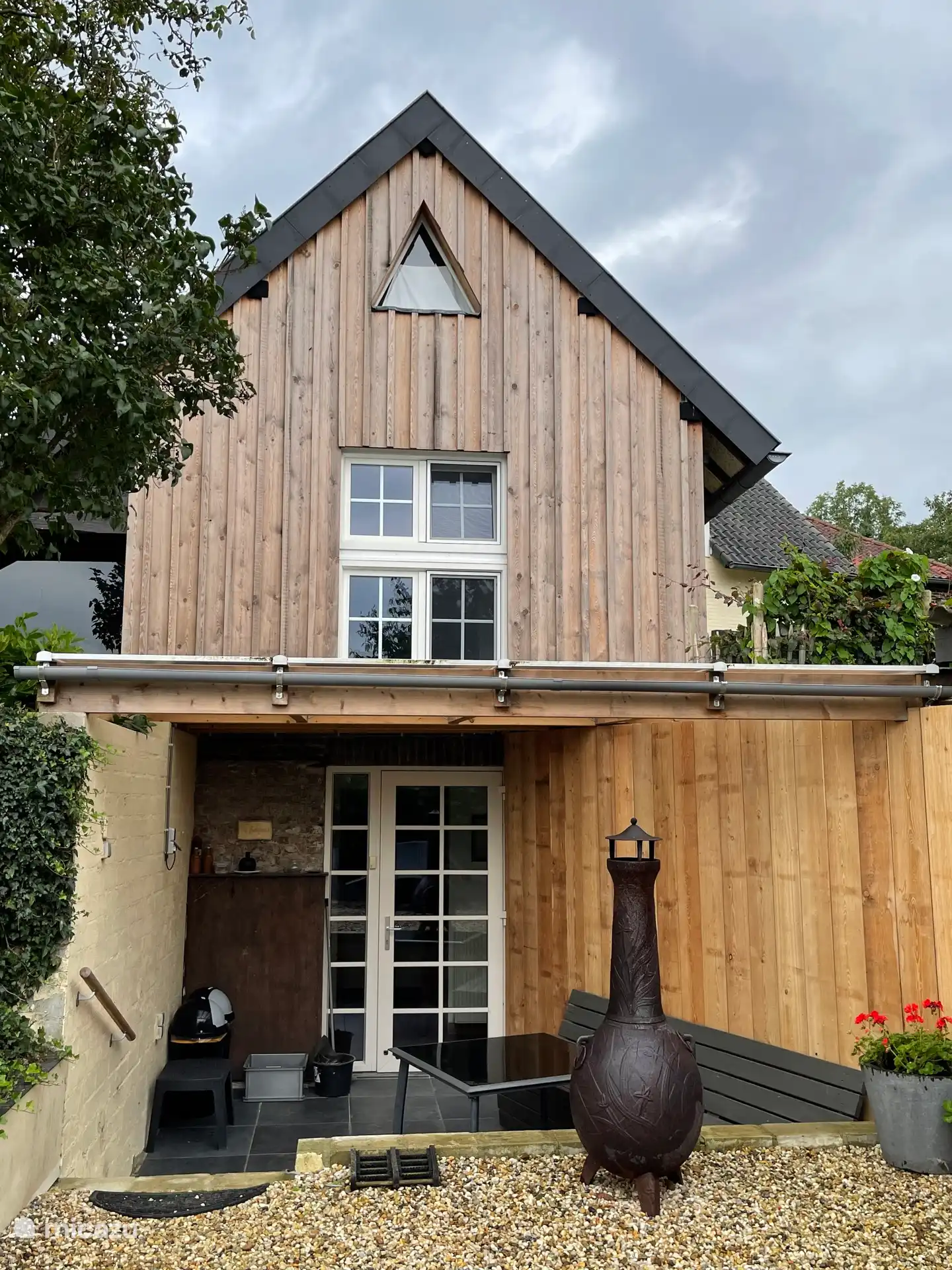 ingang huisje met afdak en houtkachel