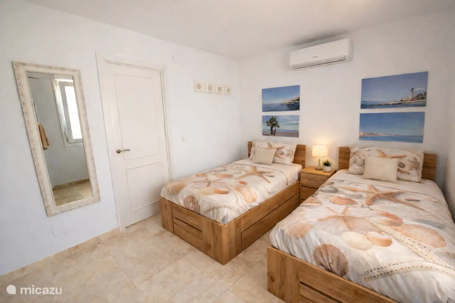 Lichte slaapkamer op de begane grond met twee comfortabele eenpersoonsbedden, airconditioning en een rustige strandstijl.