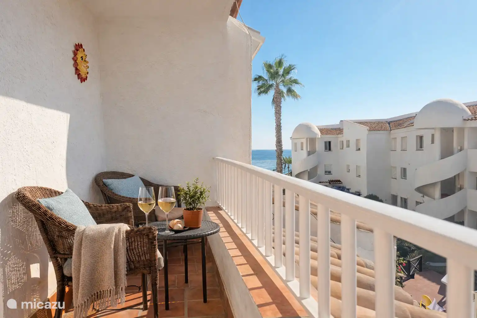 Balkon aan de slaapkamerzijde (westkant), met twee stoelen, een tafeltje en een bankje.