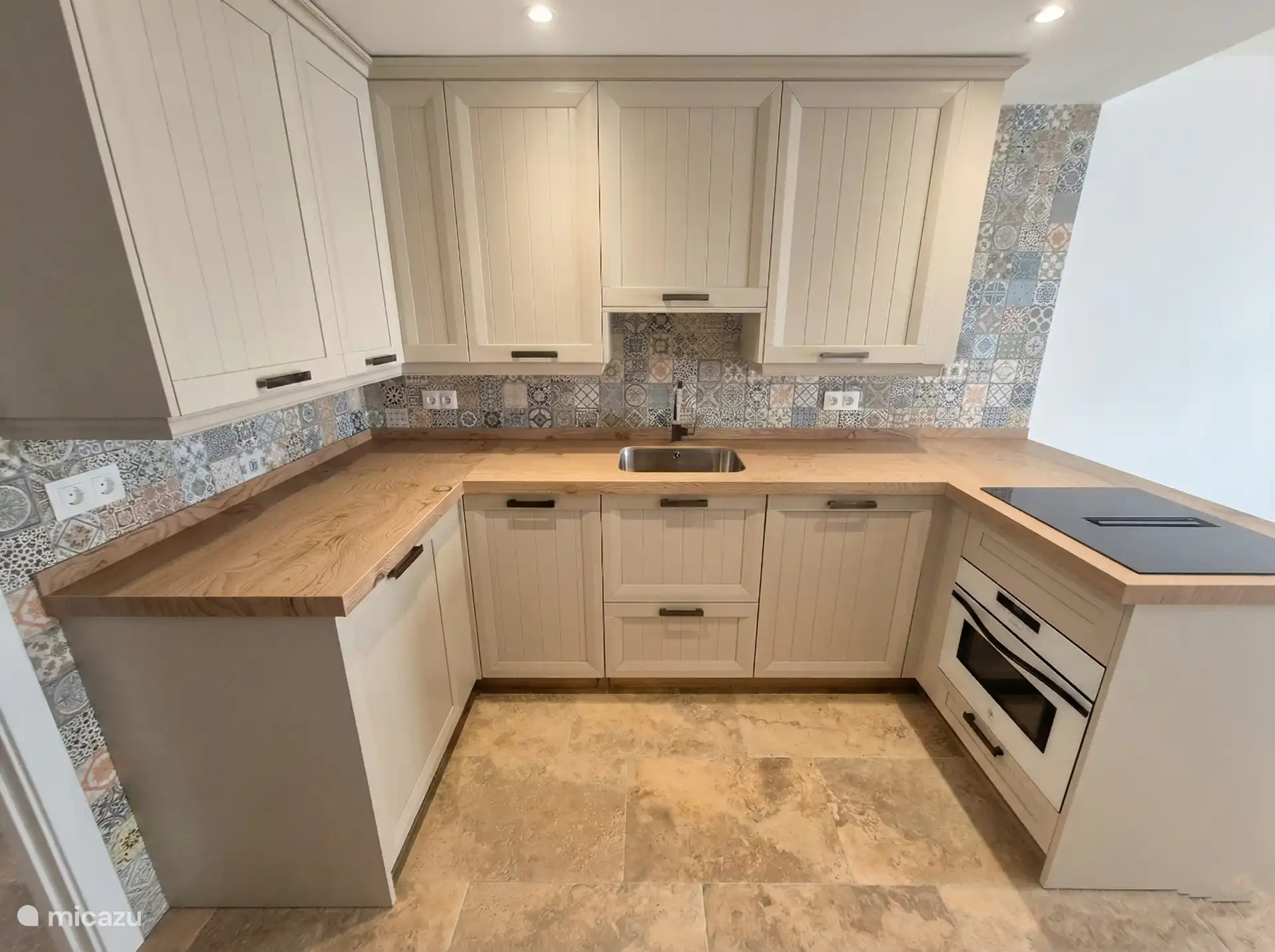 Keuken met veel werkruimte en een inductiekookplaat met geïntegreerde afzuiging.  