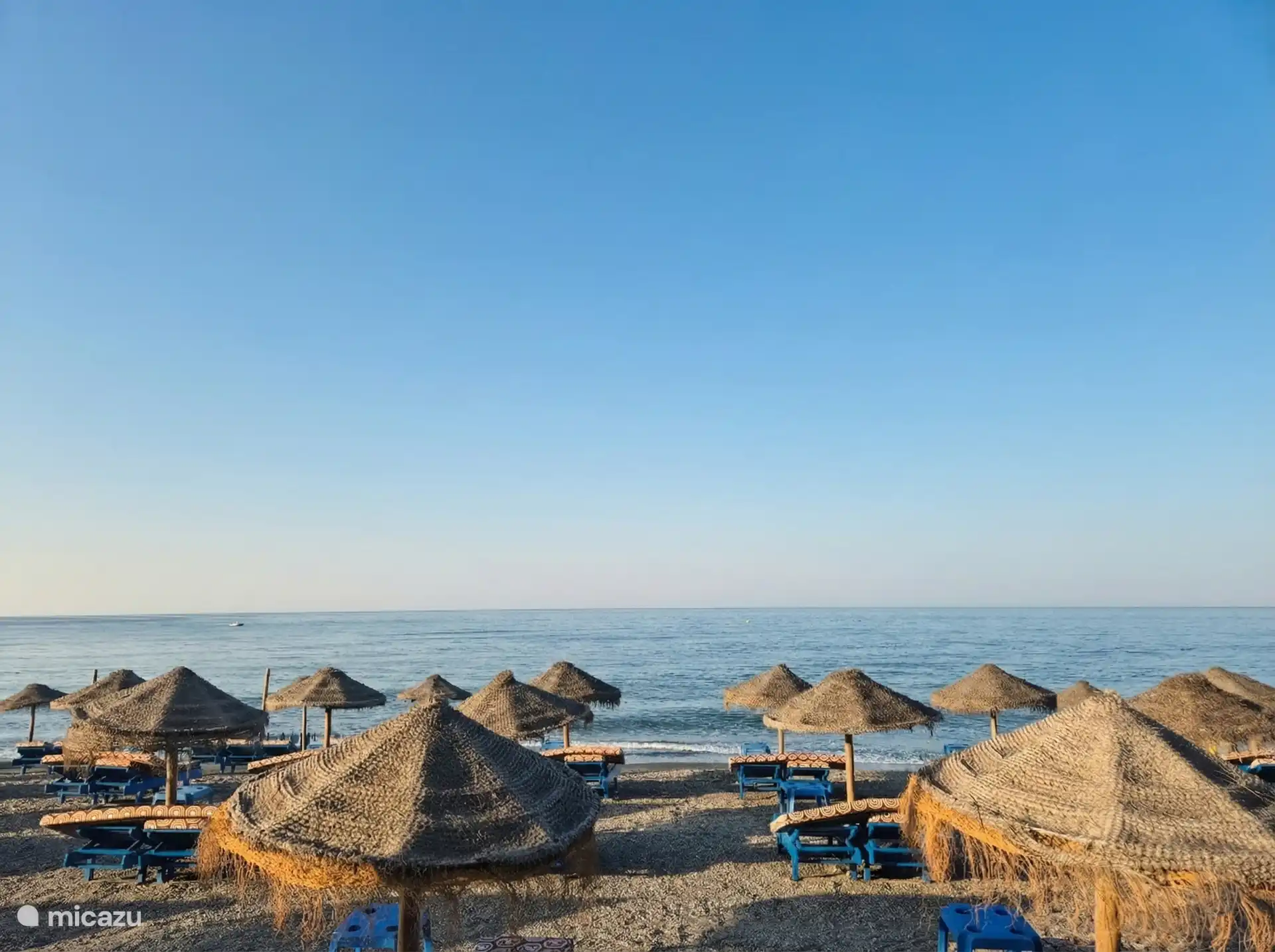Strand op korte loopafstand, met parasols en ligbedden.