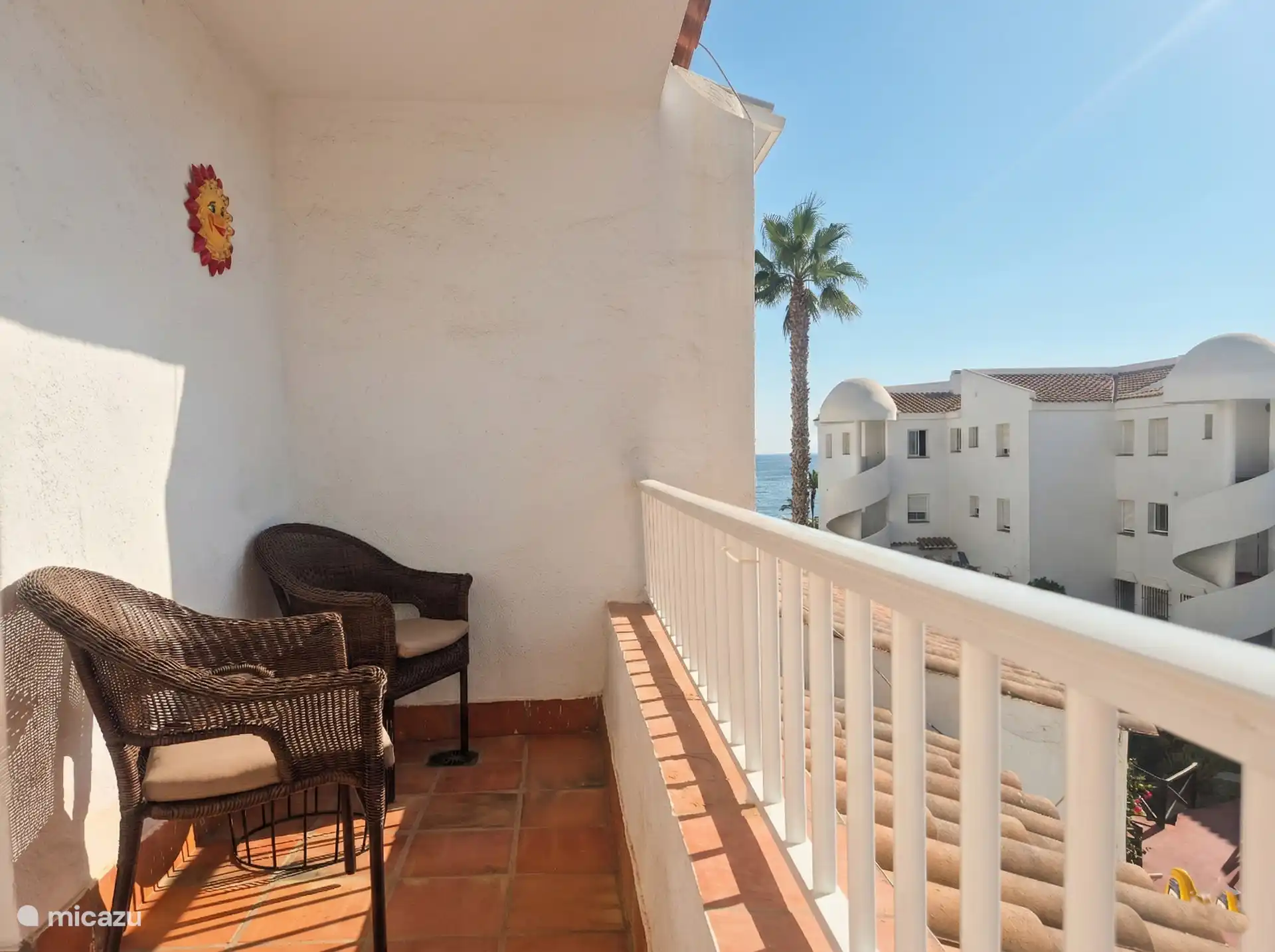 Balkon aan de slaapkamerzijde (westkant), met twee stoelen, een tafeltje en een bankje. 