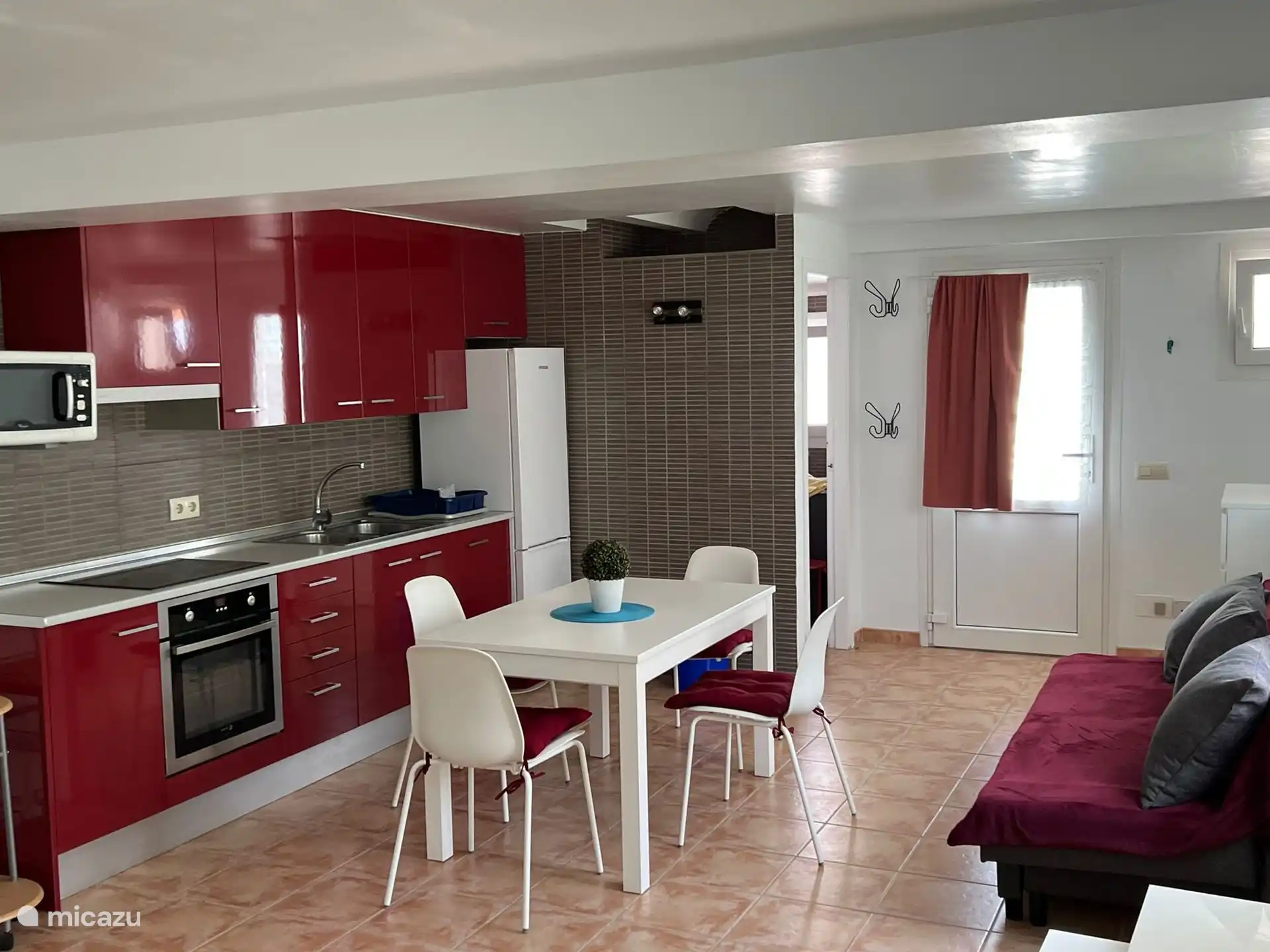 Uitzicht op de keuken met de eettafel, de bank en de ingang