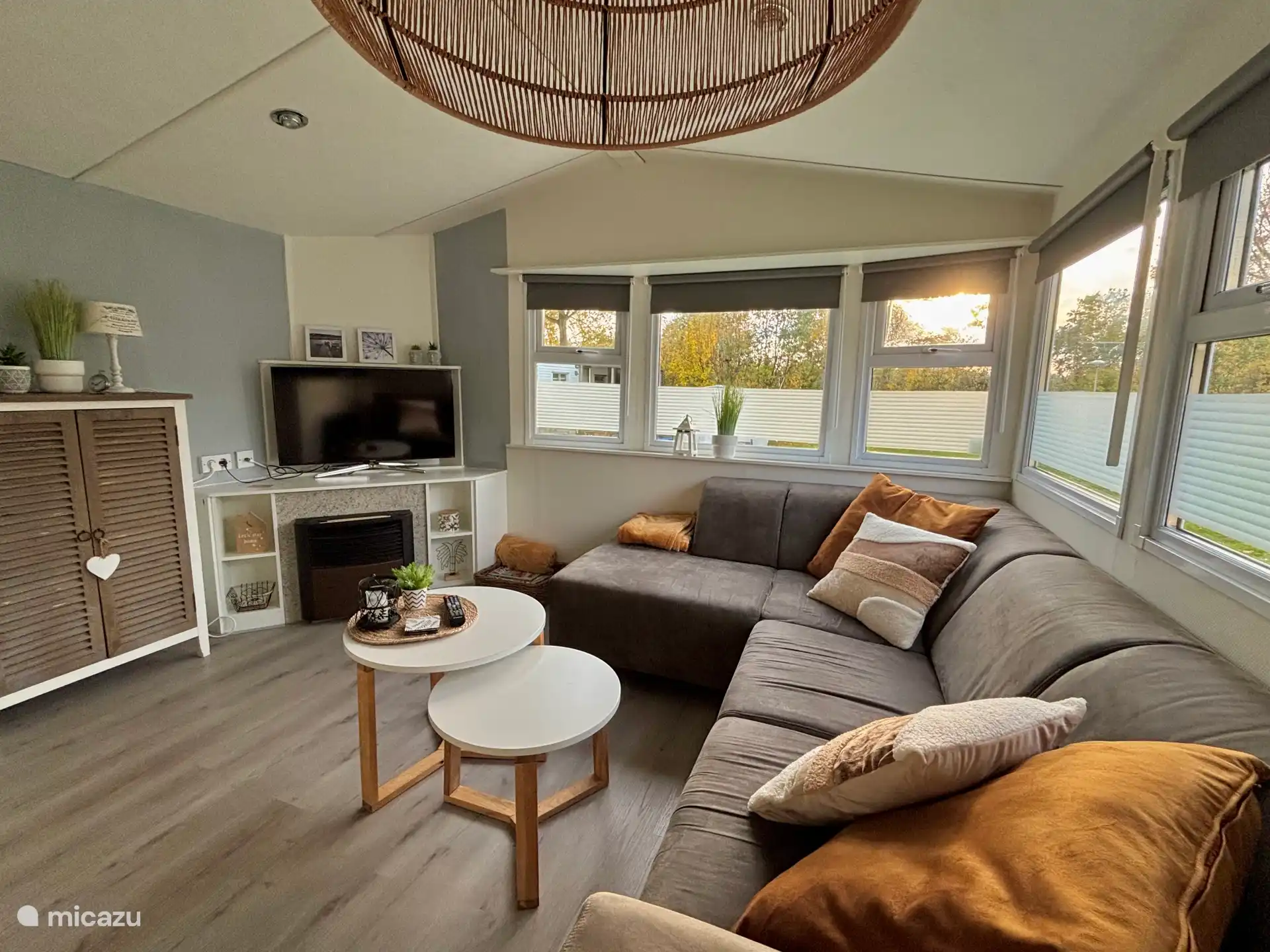 Salón con un gran sofá en forma de L, smart TV, dos mesas auxiliares y un armario de juegos lleno.