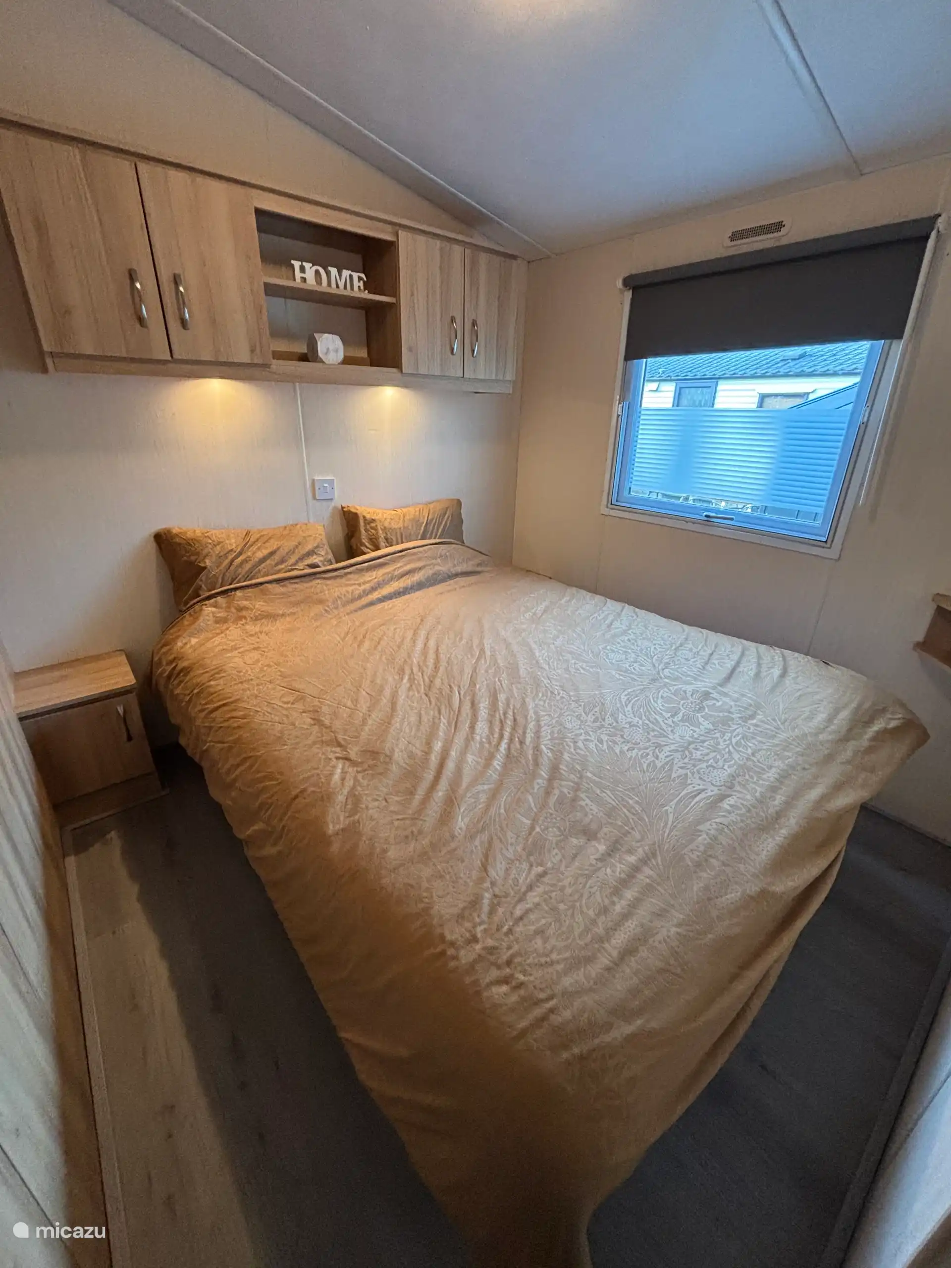 Dormitorio con cama doble, armario grande, mesillas de noche y armarios superiores.