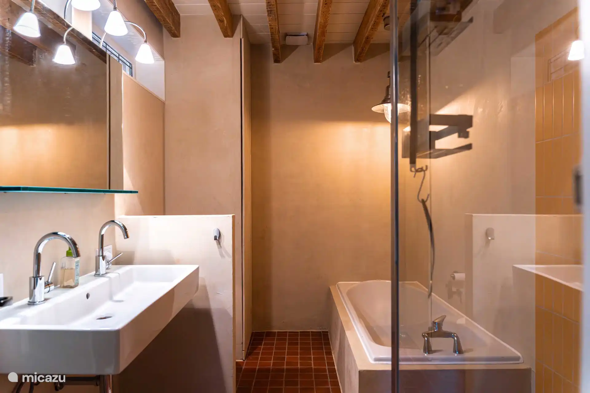 De badkamer, met bad, douche en wc