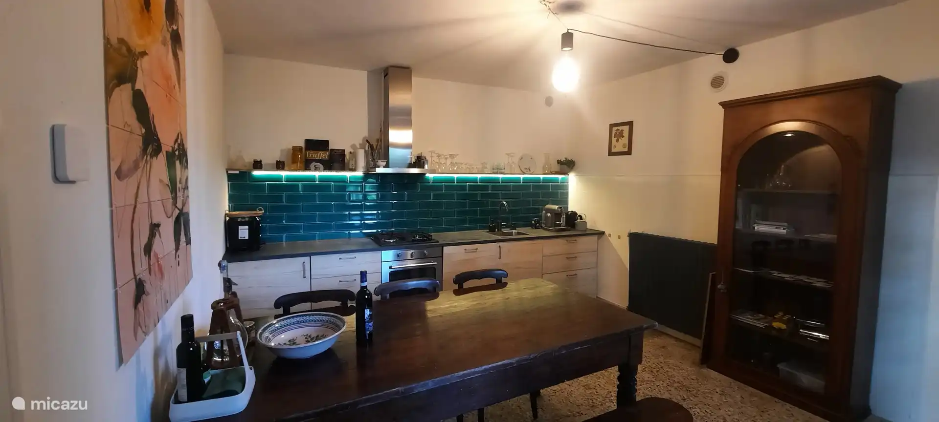 Keuken met gasfornuis, koelkast en grote tafel, maar je eet meestal buiten