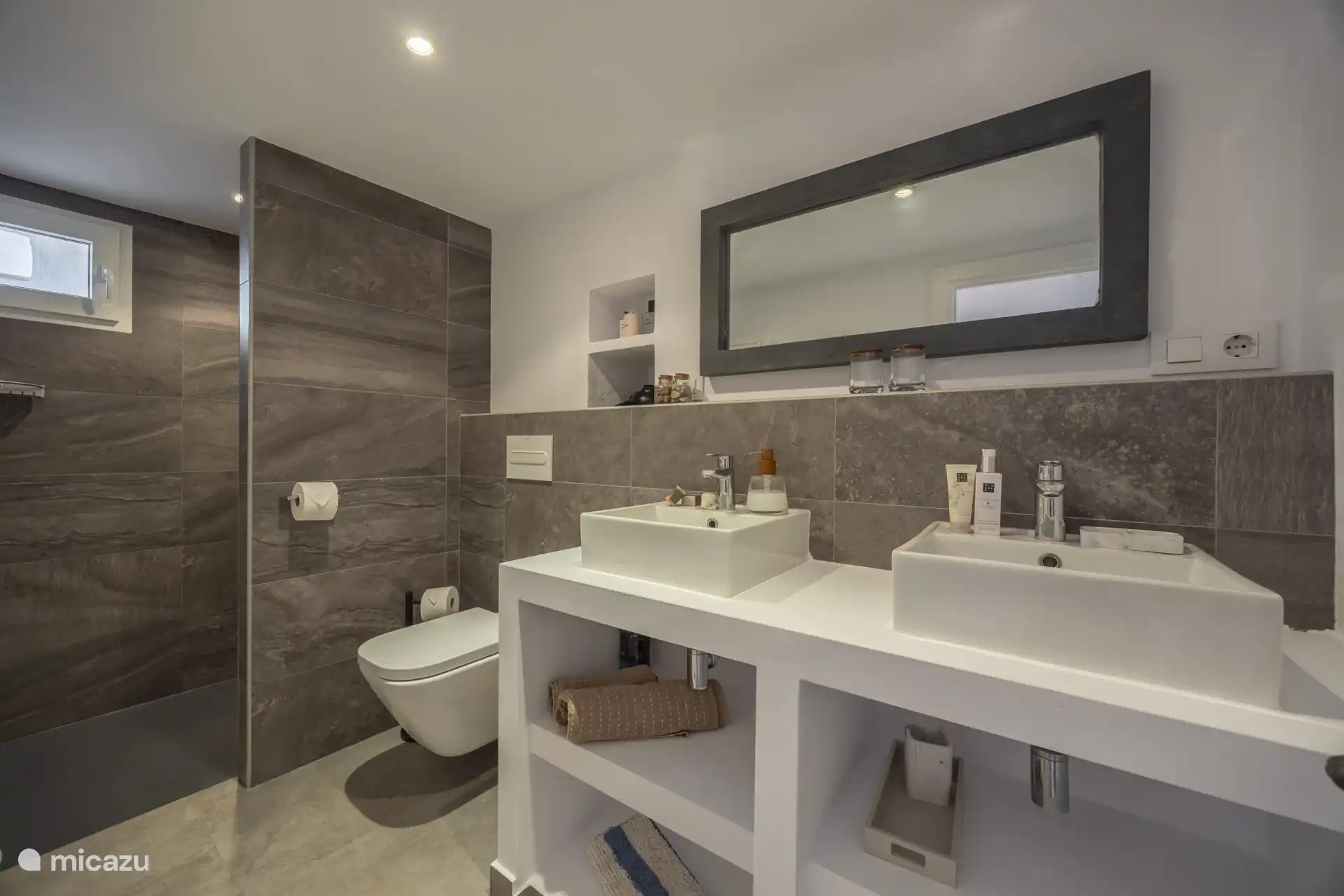 En een badkamer ensuite met douche, toilet en dubbele wastafel.