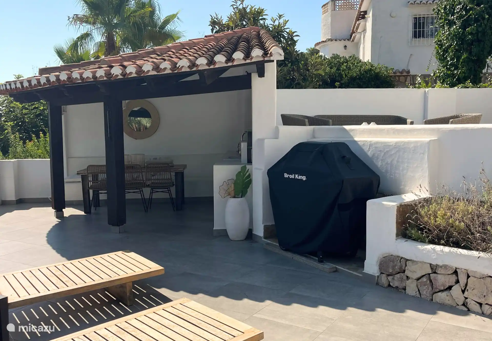 Onder de overkapping bevindt zich een ruime buitenkeuken met daarnaast een gasbarbecue.