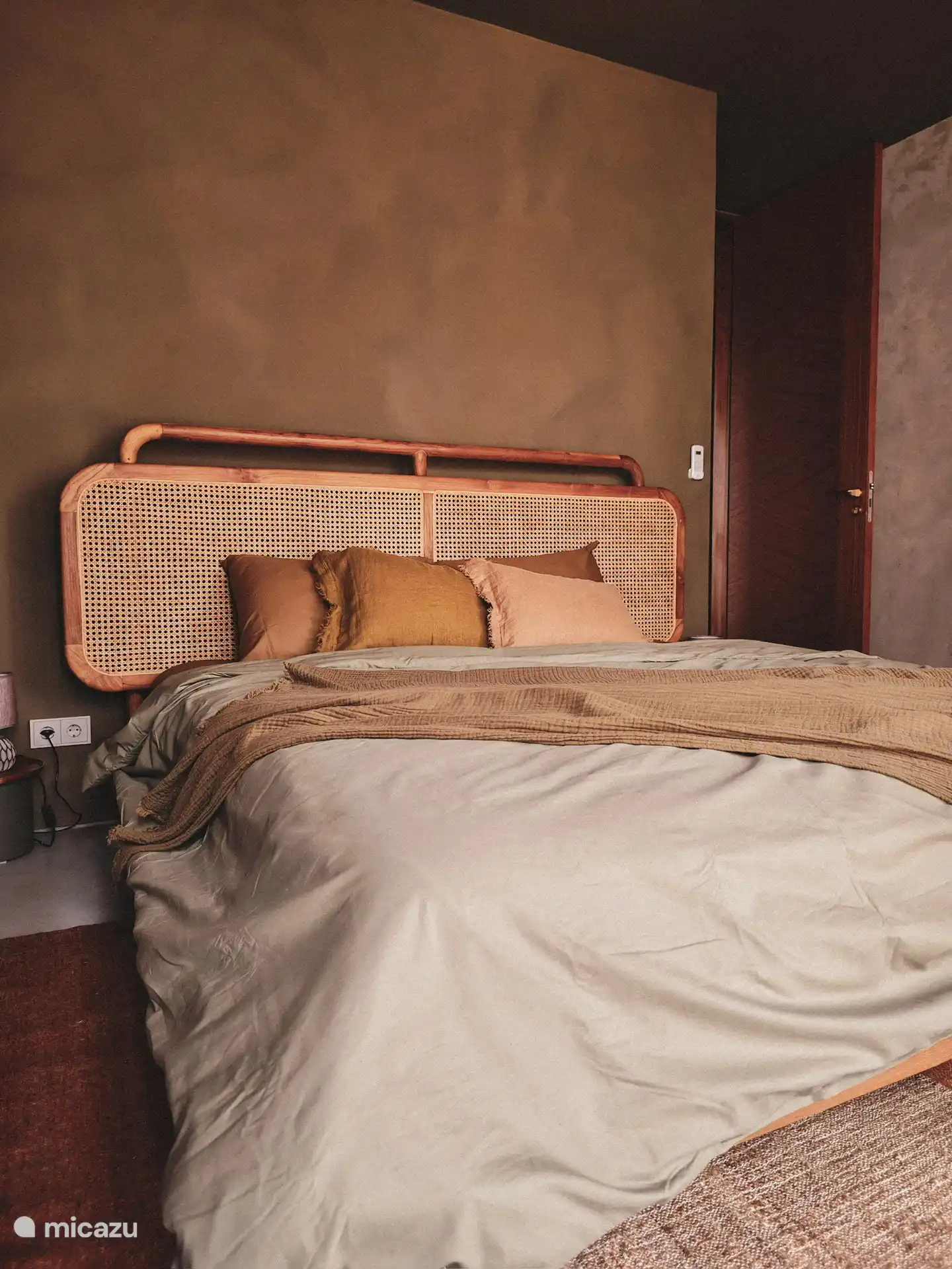 Teak king size bed and outdoor seating area with partial sea view.